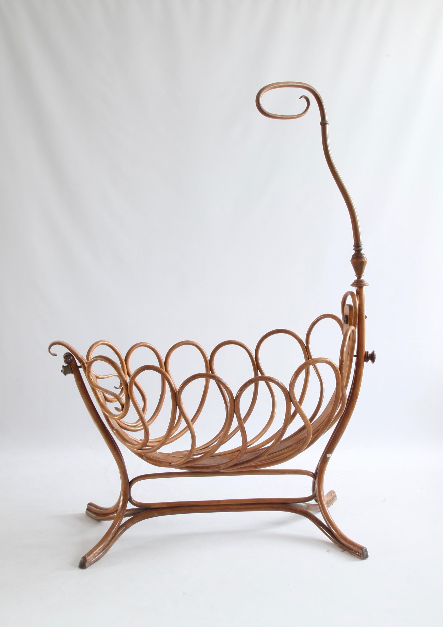 Ce berceau en bois courbé de style Thonet est une pièce rare, datant de la fin des années 1900. Le berceau est en parfait état de fonctionnement et se balance doucement, ce qui peut être bloqué par une poignée ronde (vue à l'arrière) lorsque cela