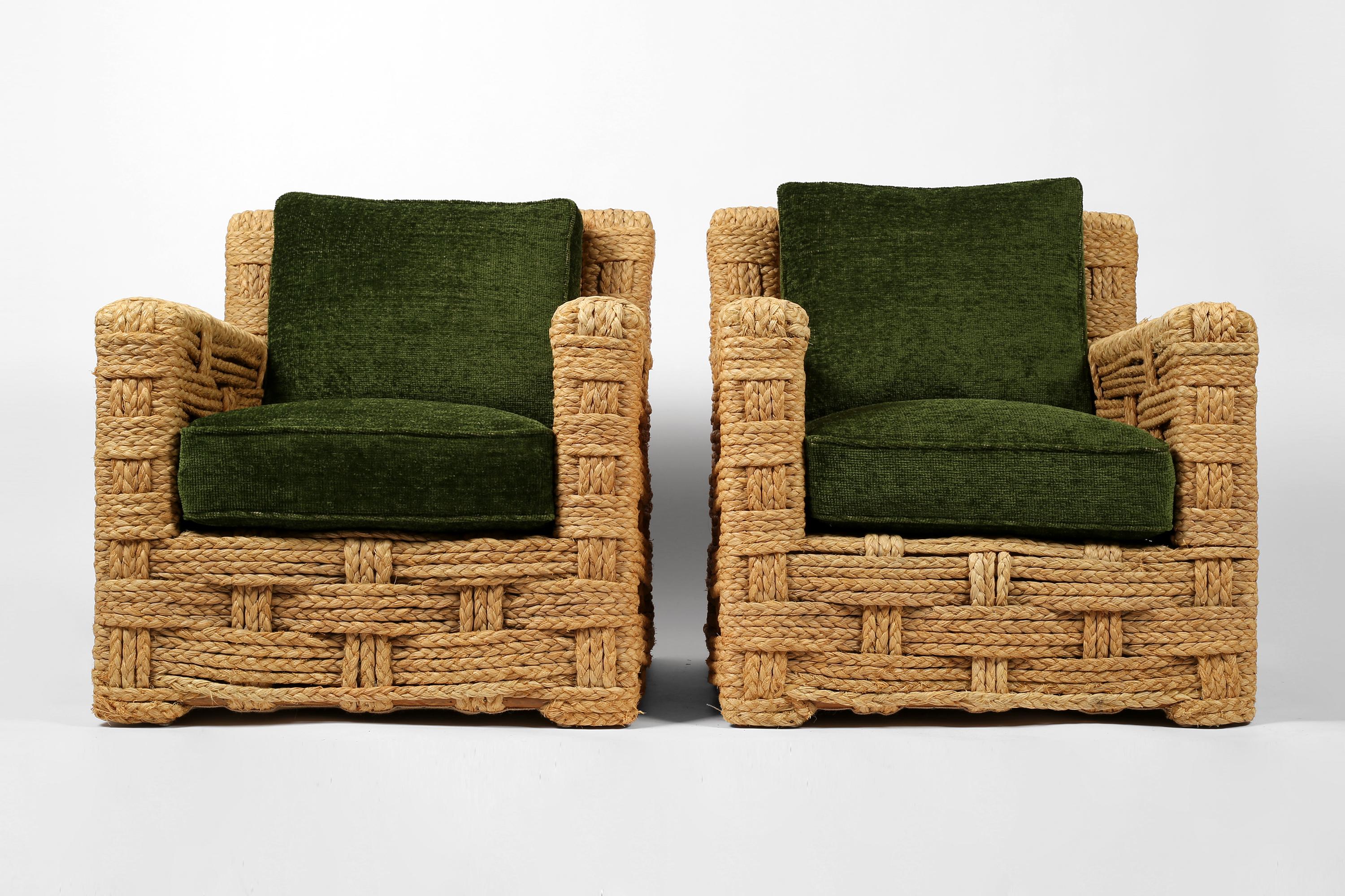 Une paire de fauteuils club très rares et de grande taille par Adrien Audoux & Frida Minnet pour leur magasin Golfe Juan sur la Côte d'Azur. Les généreuses armatures en chêne sont revêtues de leur raphia tressé d'origine. Les coussins d'assise et de