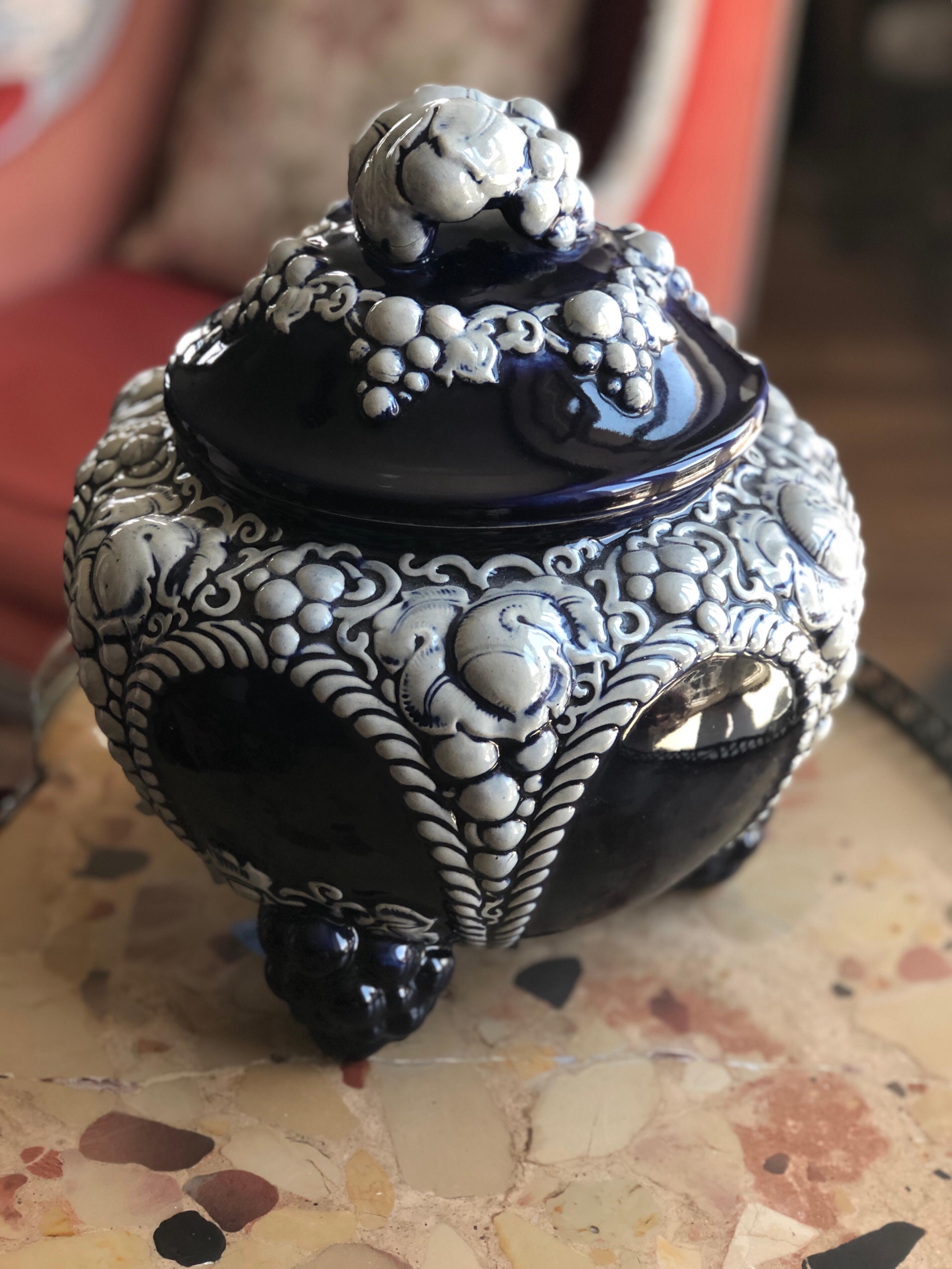 Rare handmade ceramic soup tureen standing on three legs (there is a small missing piece at one of them). The piece is richly decorated with grapes and leafs especially on the top of the tureen. It is glazed in dark blue and white and there is a