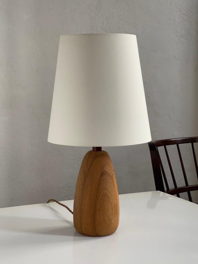 This rare French modern table lamp, carved from solid elm wood, exemplifies the innovative spirit and refined aesthetic of mid-20th century European design. The lamp's distinctive use of natural materials and its sculptural form reflect a deep