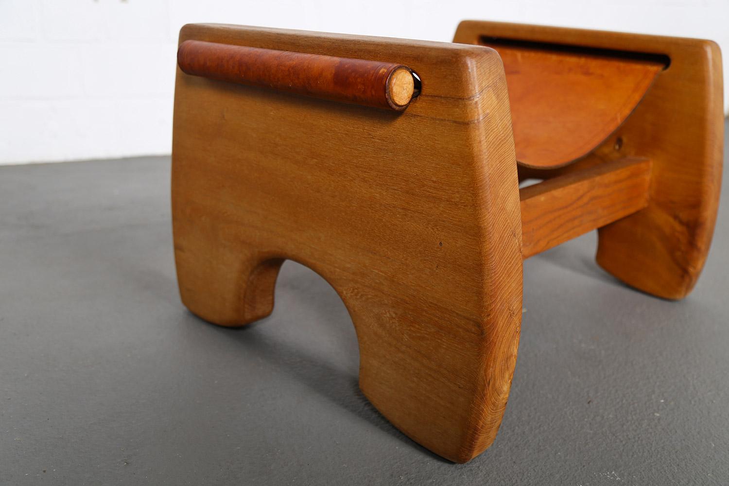 This sturdy and rustic stool – probably from the 1940s – draws its strengths both from the strong design and from the use of natural, robust materials. The sculptural, dense oak frame consists of two U-shaped side parts and horizontal connections.