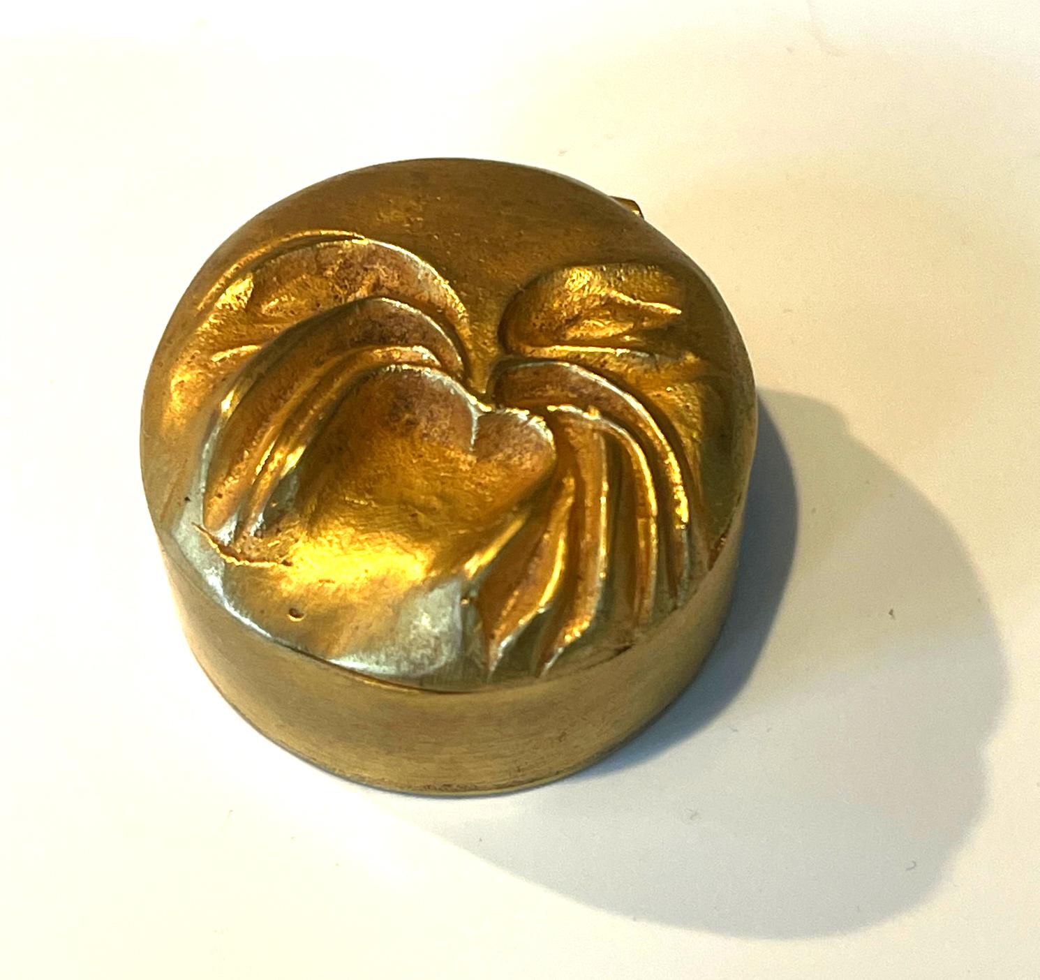 Un piccolo portapillole in bronzo dorato del gioielliere d'arte francese Line Vautrin (1913-1997) degli anni 1940-50 circa. La scatola rotonda, piuttosto rara, presenta un ragno in rilievo sul coperchio. L'interno conserva il rivestimento in sughero