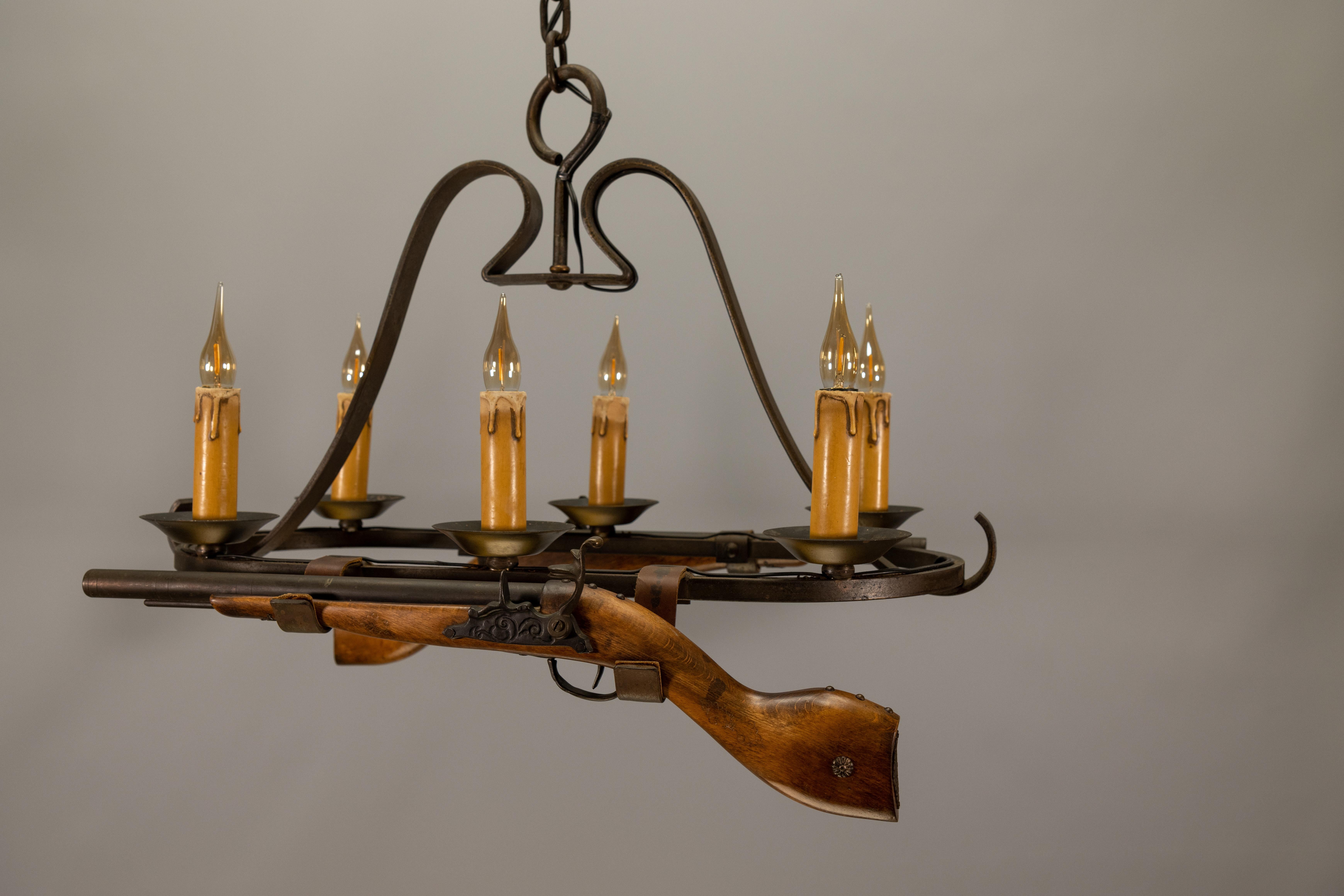 Rare 1970s French wrought iron chandelier in rustic lodge style – a bold statement piece with decorative wooden rifles.

A striking French wrought iron chandelier from the 1970s, designed in a rustic lodge style with six lights and decorative gun