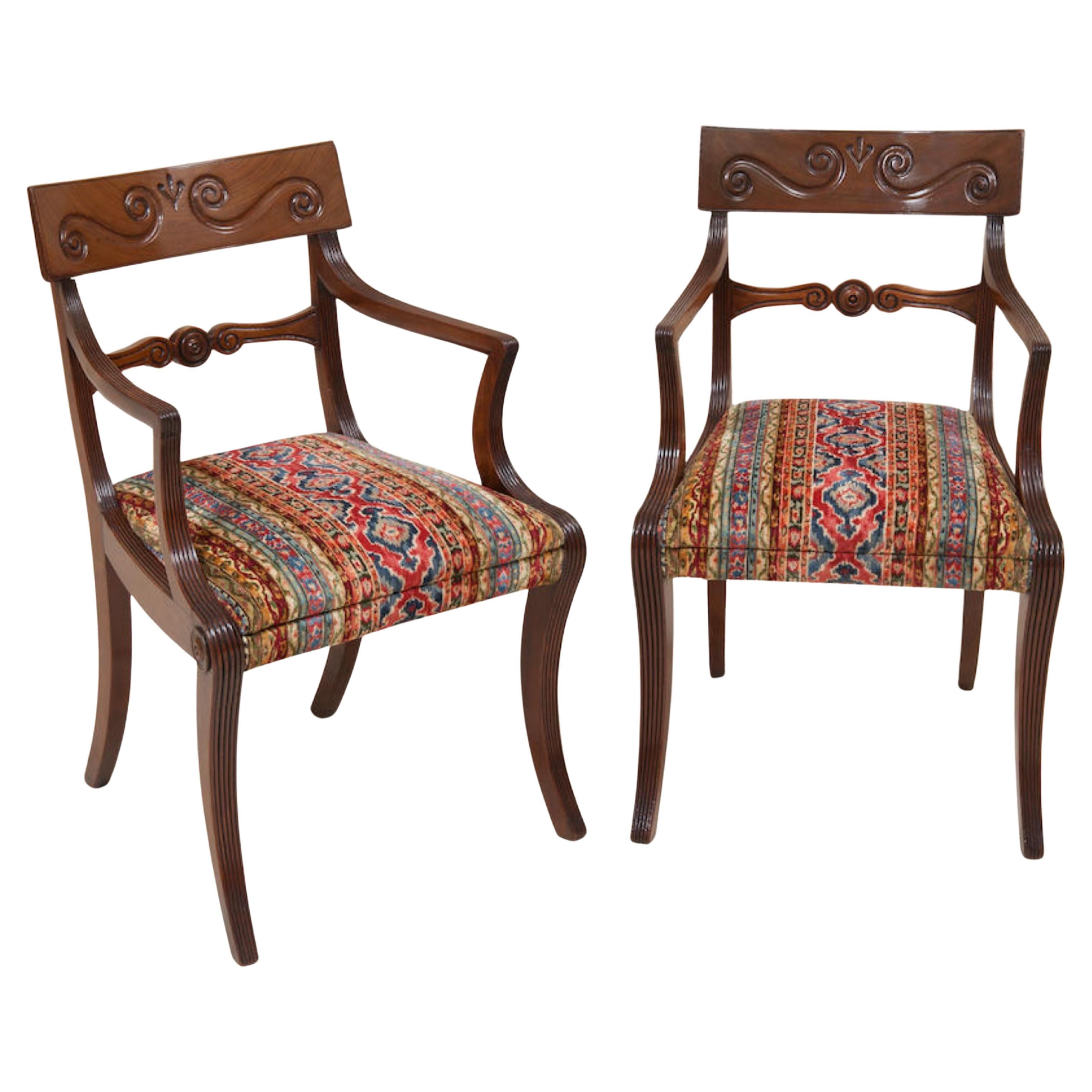 Raro set completo di 12 poltrone da pranzo a gomito in mogano intagliato del periodo Regency Sedute. Tutte le 12 sedie in mogano sono poltrone CIRCA 1820. Una barra curva con scultura S Scroll, braccioli con scanalature e gambe a sciabola con sedute