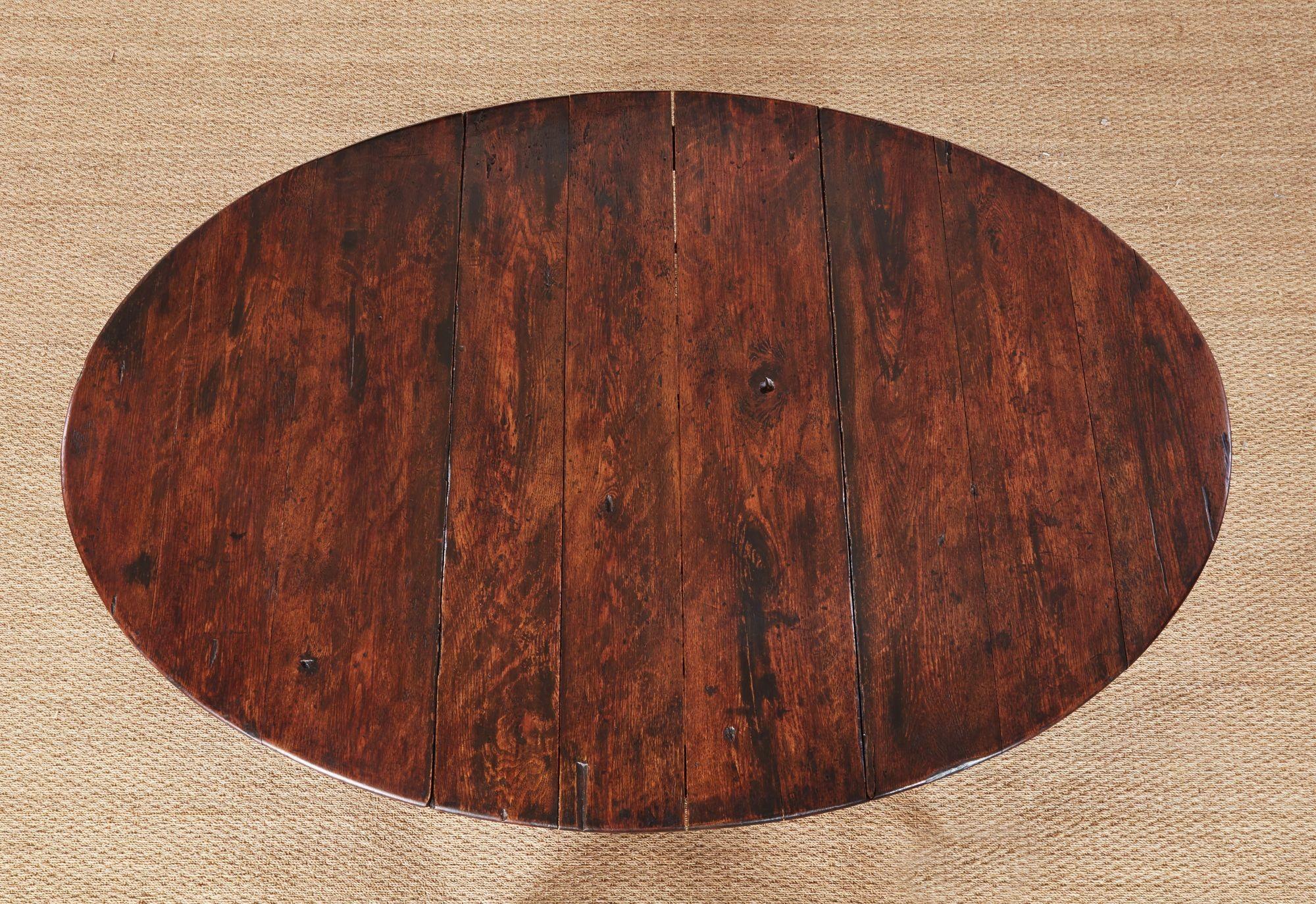17th century English oak gateleg dining table with the rare configuration of an undershelf, also known as a pot-board shelf, resting on shoe feet. Extended, the table has an oval top on baluster turned legs incorporating two D shape leaves supported