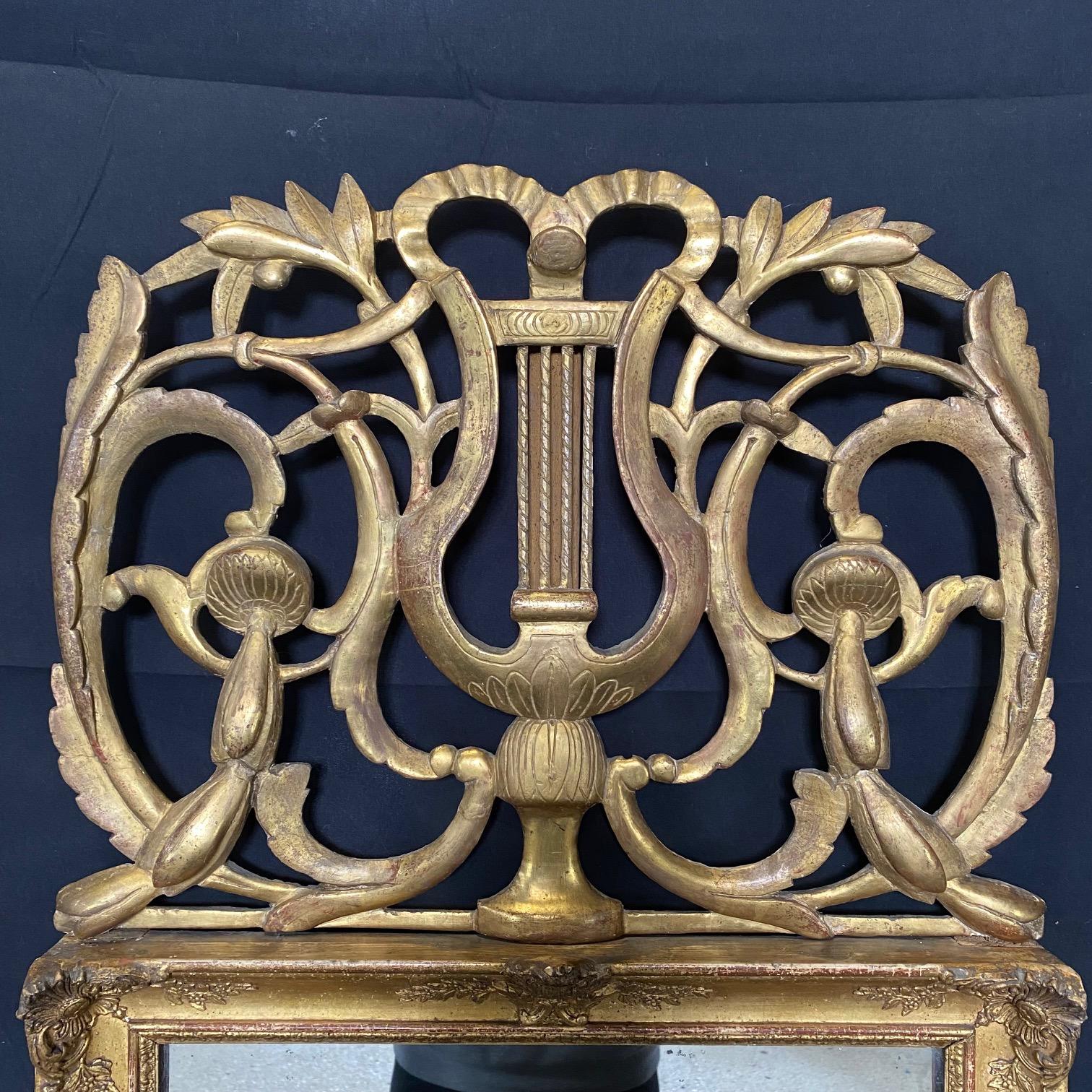 Rare forme de miroir français Louis XVI en bois sculpté et doré à la main avec un fronton qui présente une belle harpe ou lyre, des motifs floraux et une couronne de laurier. 
# 6160
Le miroir mesure 16,25 x 19 h

