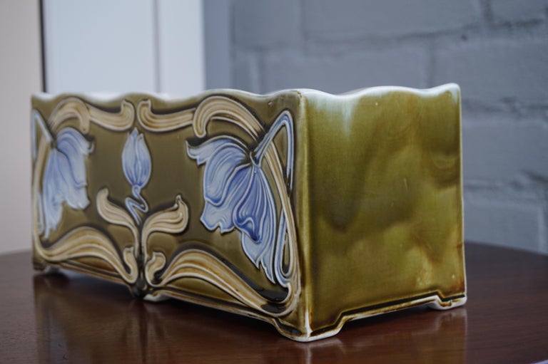Handcrafted and wonderfully decorative antique jardinière.

This stunning Majolica glazed jardinière from the German Arts & Crafts era comes with a beautiful and truly elegant decor of stylized flowers on both sides. What makes this Majolica
