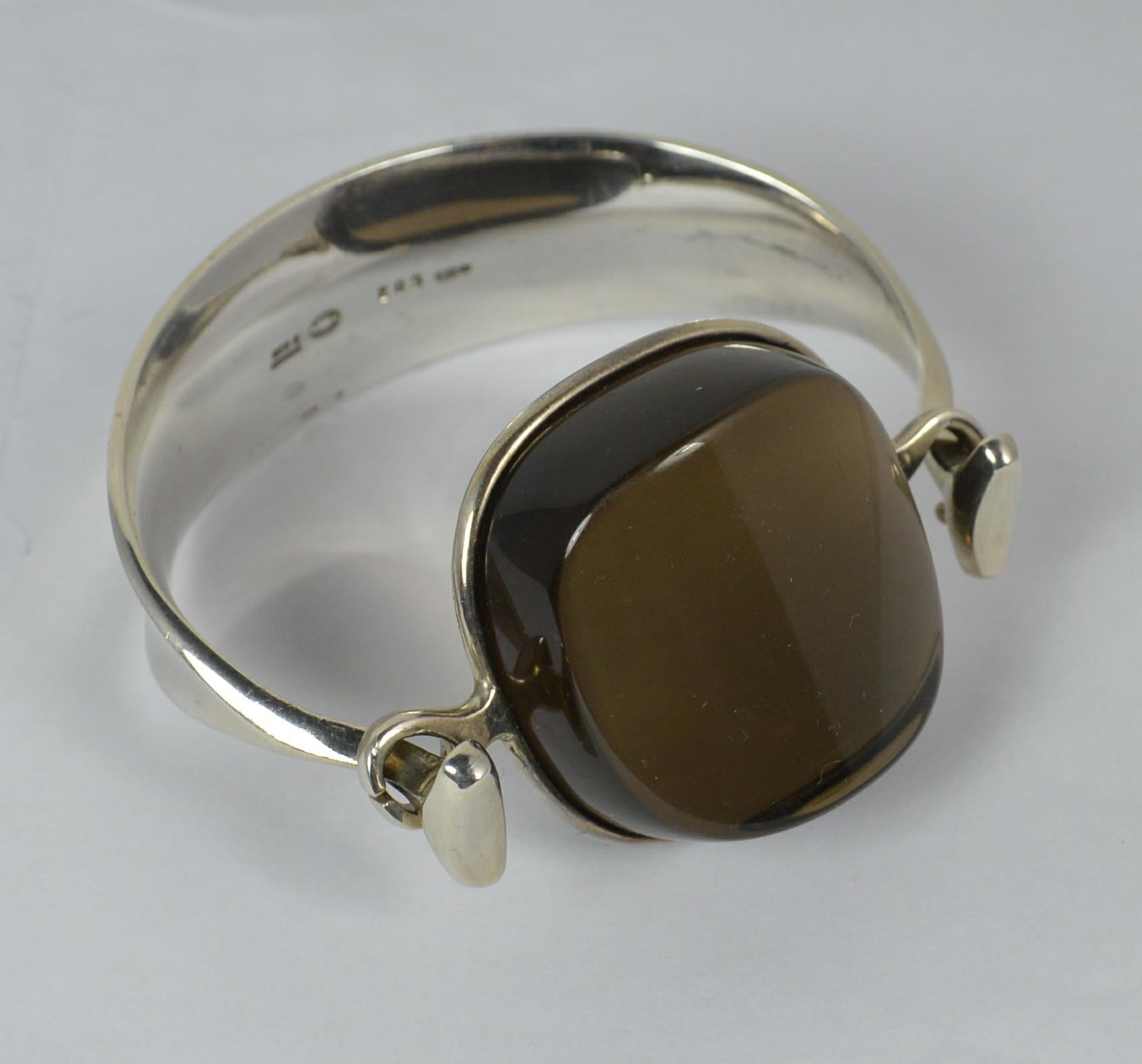 A beautiful Georg Jensen bangle.
Sterling silver example.
Set with a huge single smoky quartz stone.
Model number 203.

Hallmarks ; Torun, 203, Georg Jensen, full marks
Weight ; 78 grams
Size ; 34mm x 33mm stone. 6 1/2 inner circumference
Condition