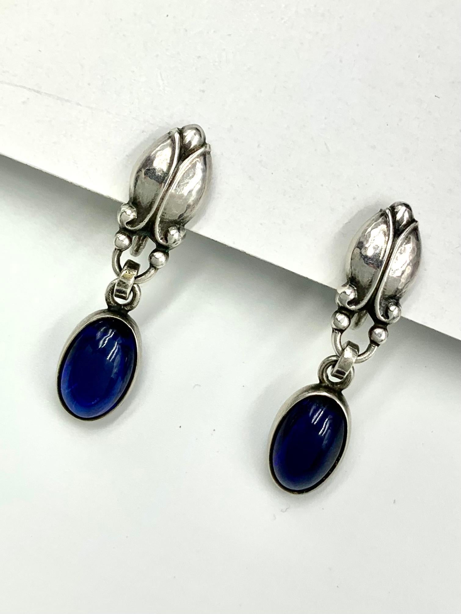 Fine, rare Georg Jensen cabochon sapphire and sterling silver Moonlight Blossom Model 17 earrings
Designed by Georg Jensen himself, this beautiful scarce model features fine silverwork and oval cabochon blue sapphires.
Marks: Georg Jensen, 17,