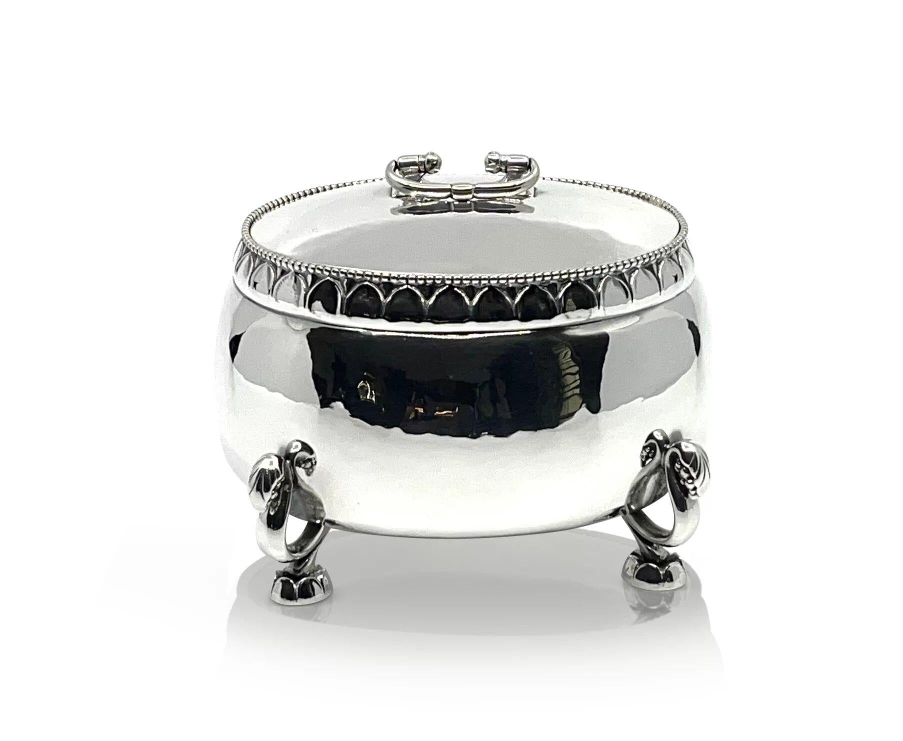 Bombonera de plata de ley Georg Jensen grande y muy antigua, diseño nº 298 de Georg Jensen de hacia 1927. Gran bombonera oval martillada a mano, la tapa se levanta, el asa es abatible. El borde es de cuentas y está cincelado; los pies están