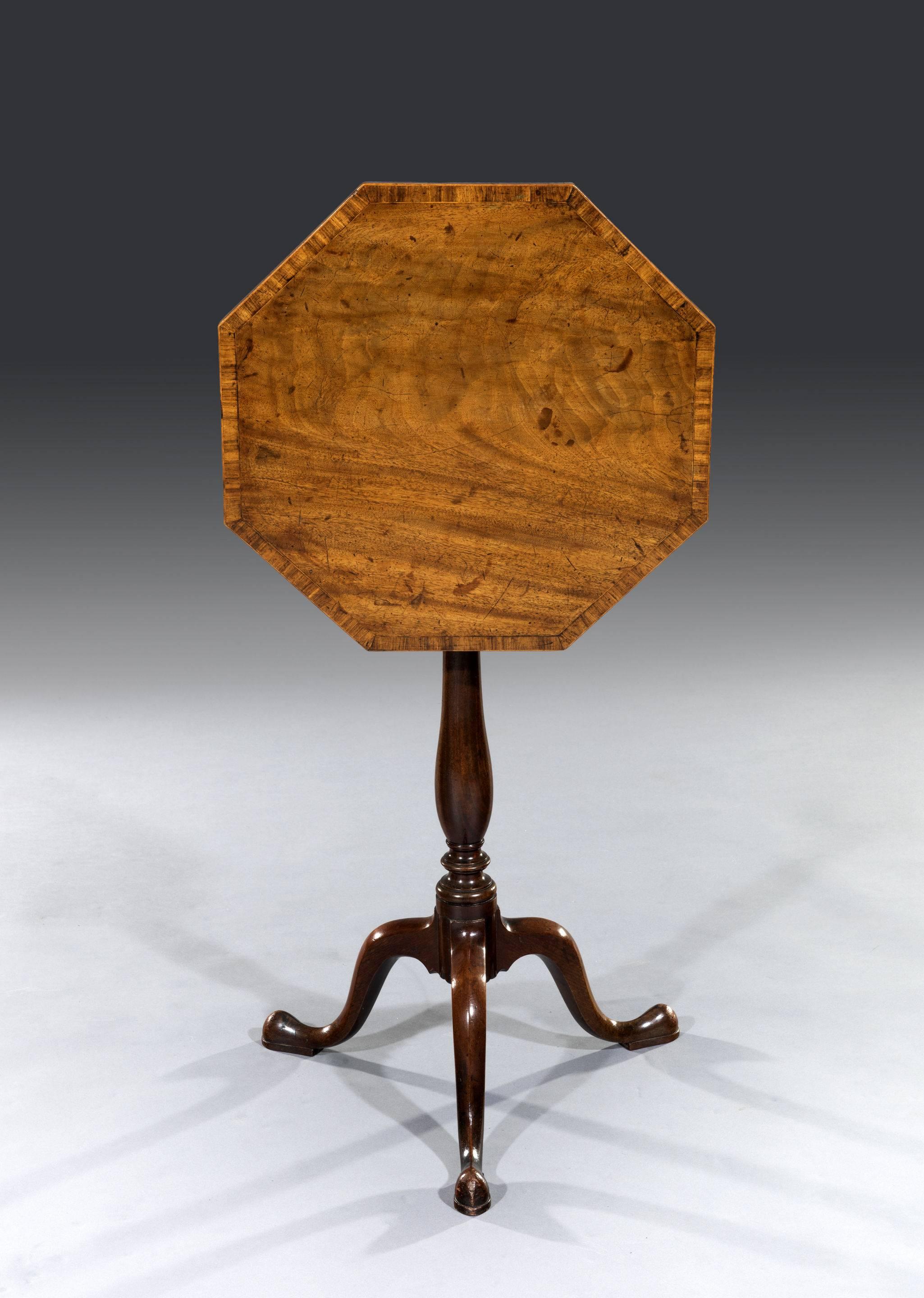 The faded flamed mahogany top is cross-banded in tulipwood and boxwood stringing and retains a great colour and patina. The tilt-top table sits on its original saddle and retains the original locking mechanism that keeps the table top locked down.