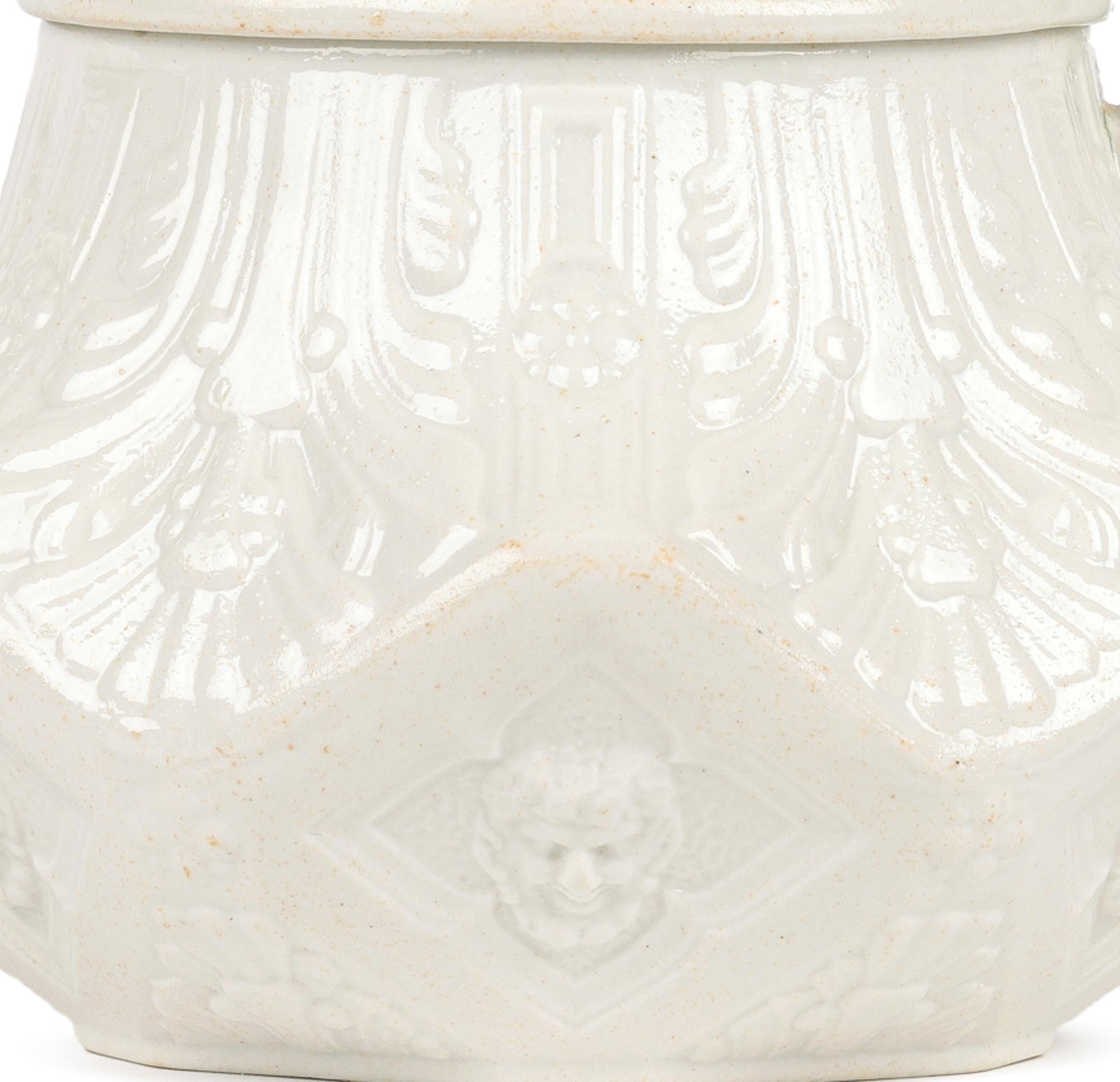 Una rara teiera georgiana inglese con pannello smaltato al sale e decorata con maschere di Bacco, realizzata dal famoso produttore Wedgwood e risalente al 1760 circa. La teiera in gres bianco di piccole dimensioni poggia su una stretta base a forma