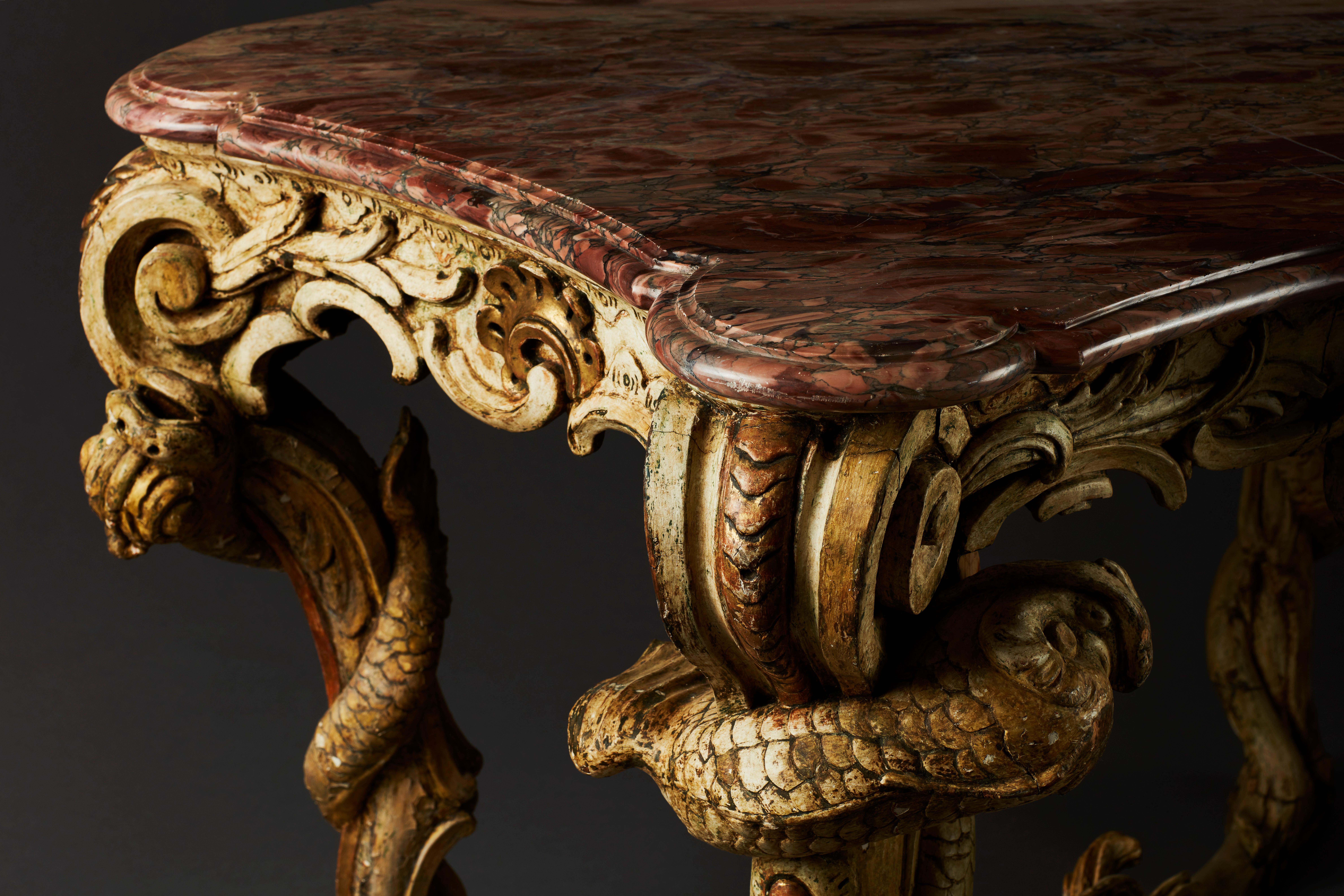 A very unusual and superb Rococo console table from the mid-18th century. On four carved legs with an X-shaped stretcher, overall with scrolls and dolphin-like sea creatures. This extravagant console table recalls features of fantastic 18th century
