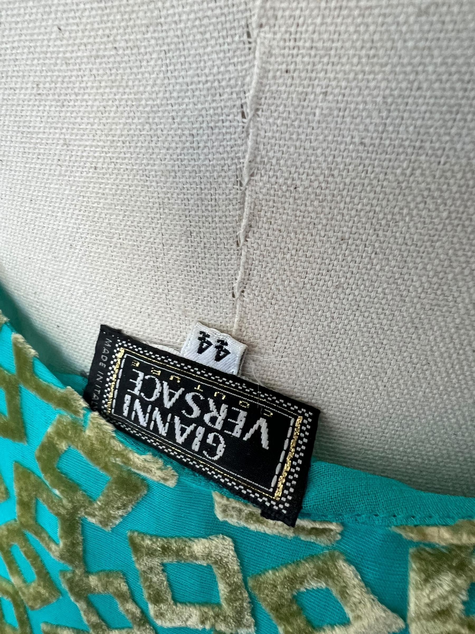 
Cette exquise robe vintage Versace de 1999 illustre la vision audacieuse et luxueuse de Donatella Versace en matière de design. Fabrice en velours vert brûlé, il présente un élégant ourlet long et asymétrique qui forme gracieusement une traîne
