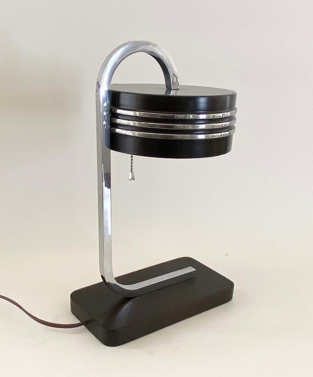 Here is a rare and handsome desk or table lamp by the American master designer, Gilbert Rhode. This chrome, enamel and lacquer example epitomizes machine age style is dates from around 1935. The lamp has been sensitively restored to its original