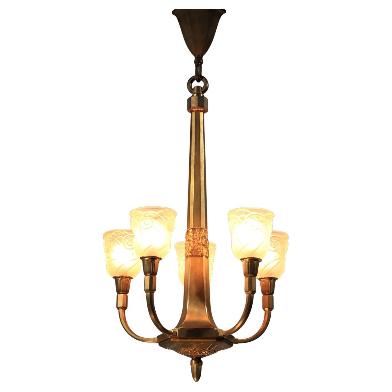 Imposing Art Deco chandelier from the 1930s, signed J. Coduré, a Lyon silversmith of the period. Gilded bronze structure (the chandelier is quite heavy) with a central frieze featuring floral motifs. 5 white frosted glass shades, created using a