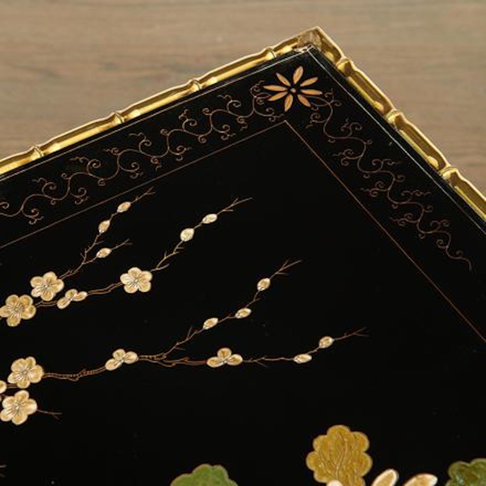 Rara mesa de centro de bronce dorado imitación bambú de Maison Baguès, tapa lacada en negro con motivos de crisantemos.
  