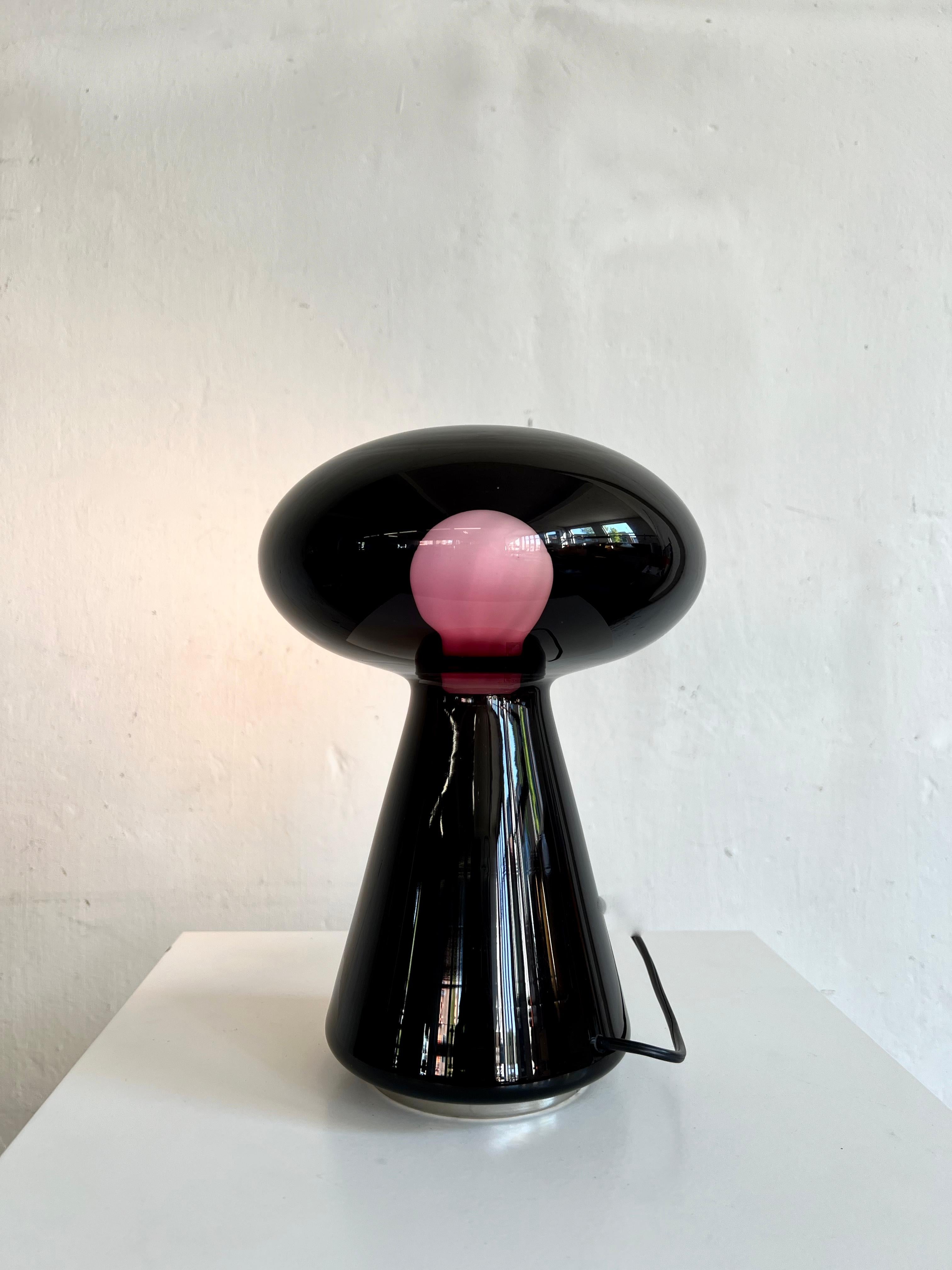 Very rare table lamp in black-purple mouth blown glass by Vistosi, 1970. Designed by Michael Red. Model L423.
 
The glass appears to be black but when switched on it shows purple around the bulb. Amazing quality in both design and quality.

It oozes