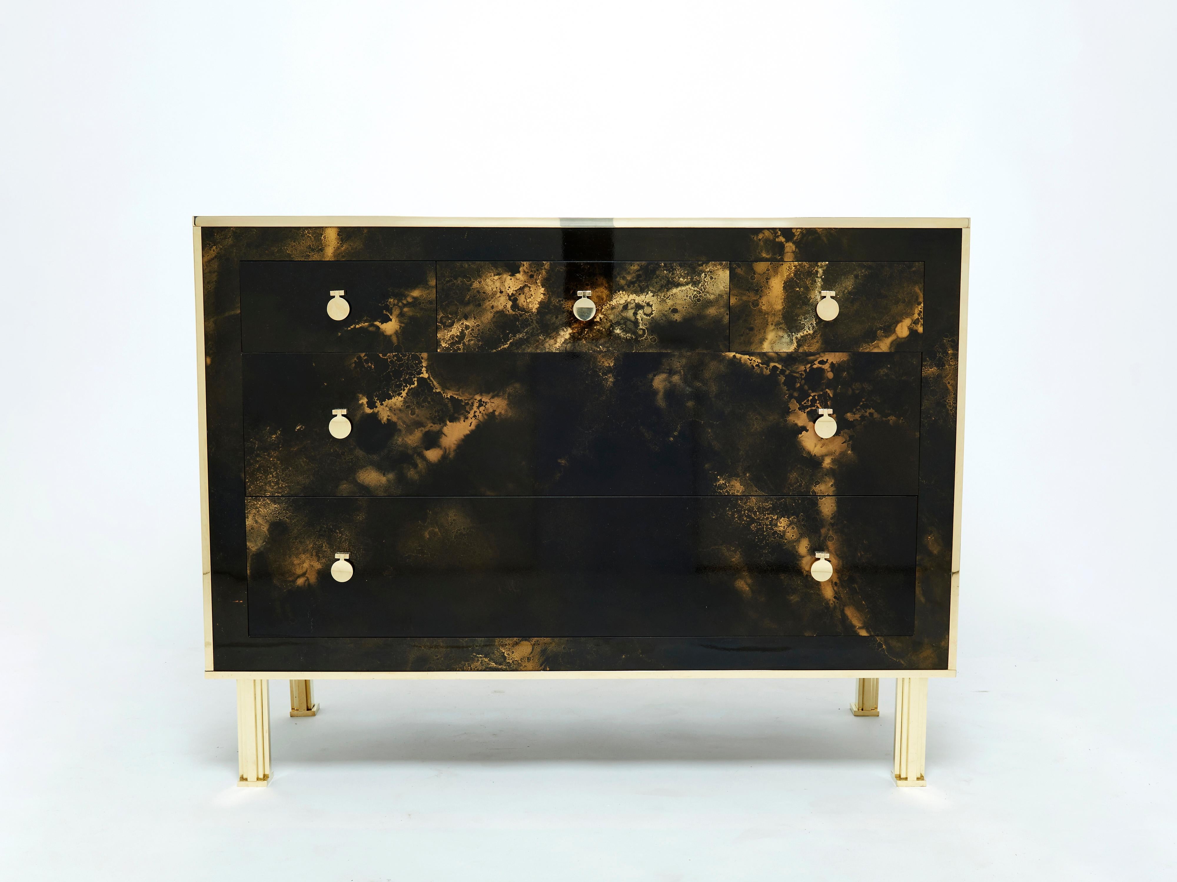 An exciting example of French design firm Maison Jansen’s commissioned pieces. This chest of drawers is made from solid mahogany, lacquered in a rich dark brown and bronze–golden finish. The resulting effect is a beautiful mottling of color around
