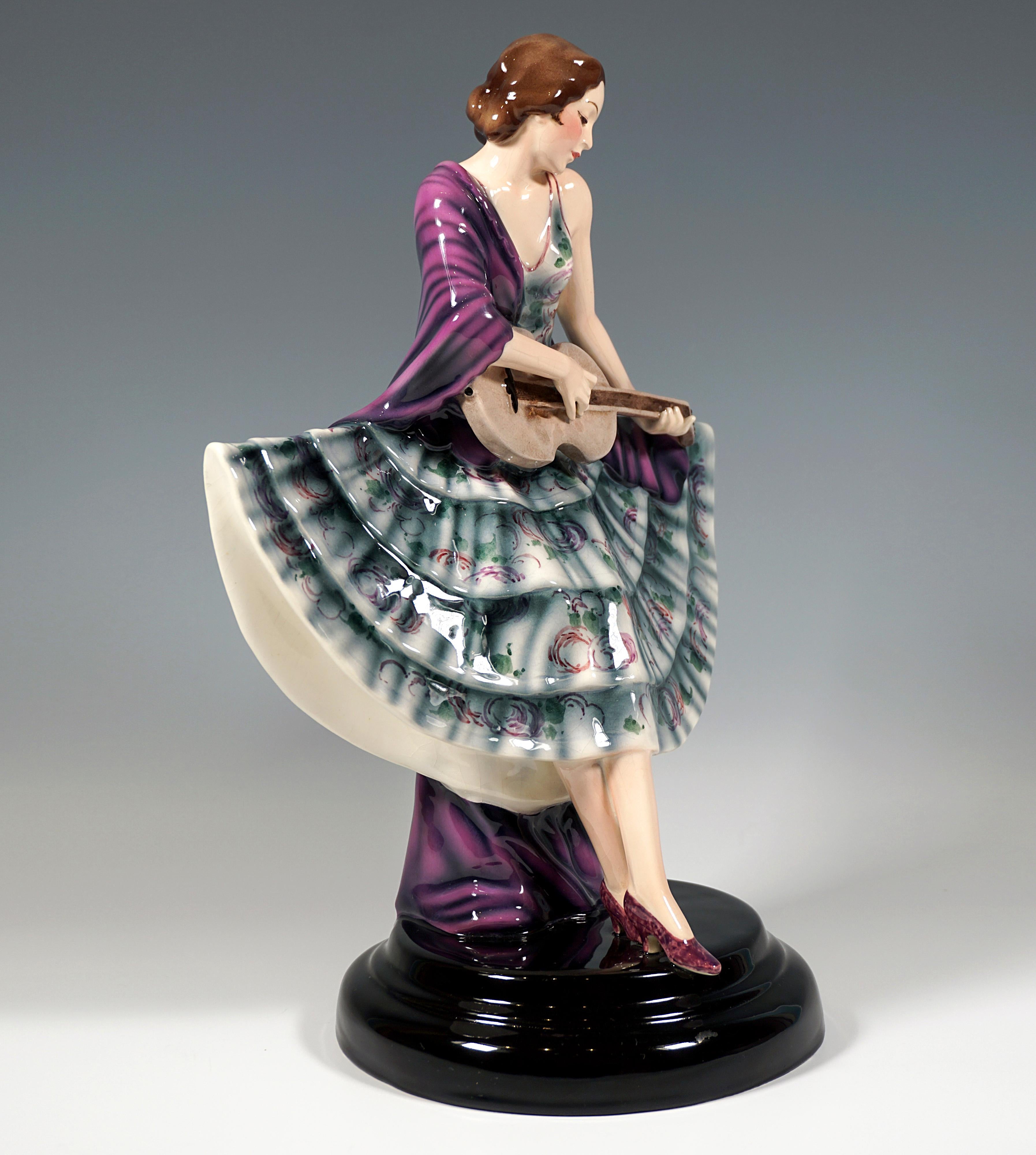 Rara statuetta Goldscheider Art Déco del 1930 circa:
Ballerina con capelli castani appuntati sulla nuca in un abito svasato a ventaglio con balze e decorazioni floreali, appoggiata a un piedistallo completamente coperto dal suo ampio scialle e che