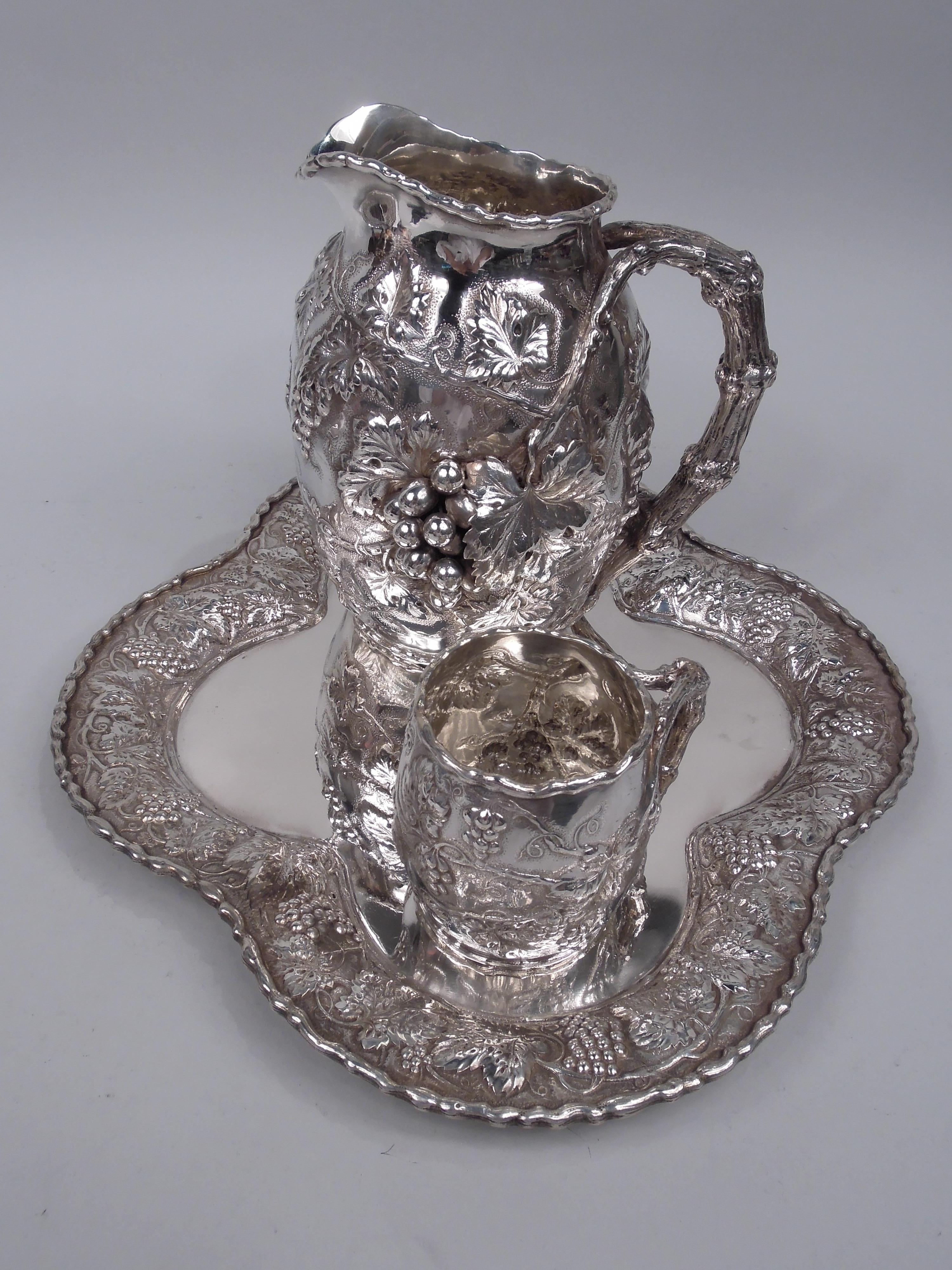 Victorian sterling silver drinks set. Made by Gorham in Providence in 1888. This set comprises pitcher and mug on tray. Pitcher and mug have curved bodies and split-mounted branch handles. Tray lobed quatrefoil. Applied scroll rims. For fermented