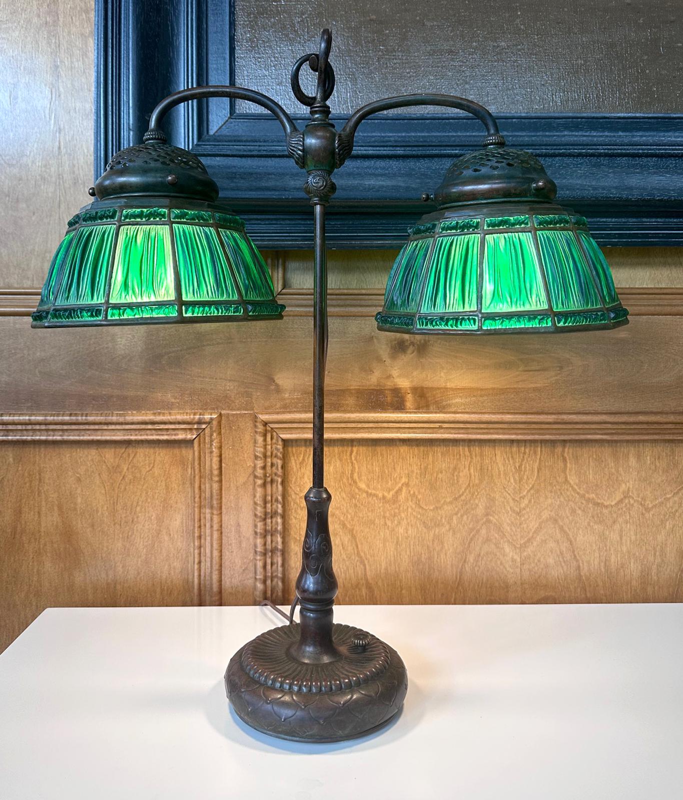 A Linenfold Favrile glass double student lamp from Tiffany Studio (1878-1933) circa 1910s. This rare model features two matching green colored linenfold glass shades (approximately 9.5