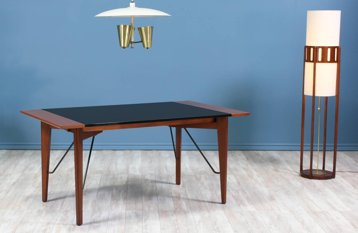 Dining table designed by Greta M. Grossman for Glenn of California in the United States circa 1950’s. This extraordinary dining has been newly refinished by our team of experts. The table features a solid walnut wood frame with a black laminate top