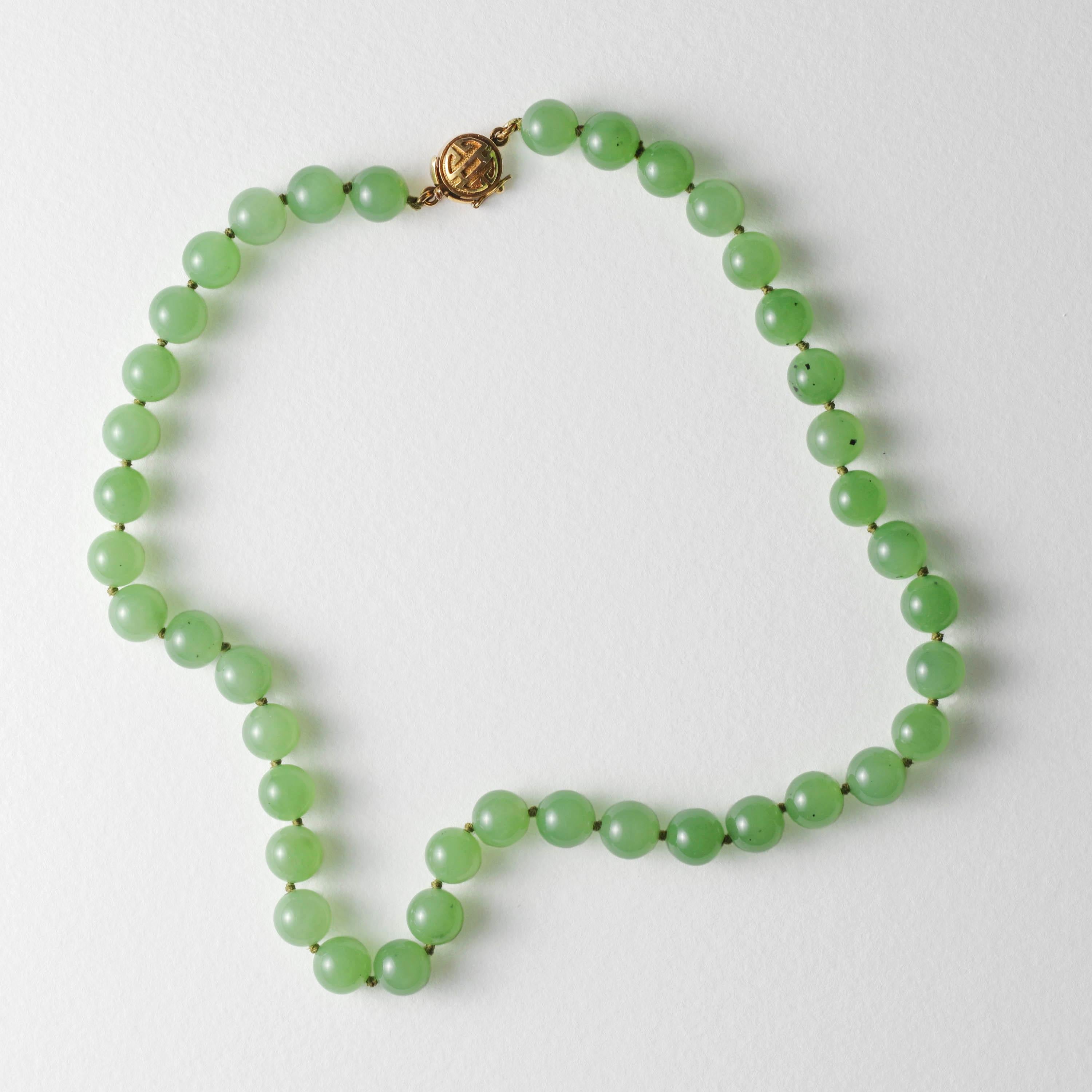 Ce rare collier en jade néphrite de Gump, datant du milieu du siècle dernier (vers les années 1960), est d'un vert chartreuse clair exceptionnellement translucide. En effet, les perles sculptées et polies à la main sont si translucides qu'elles