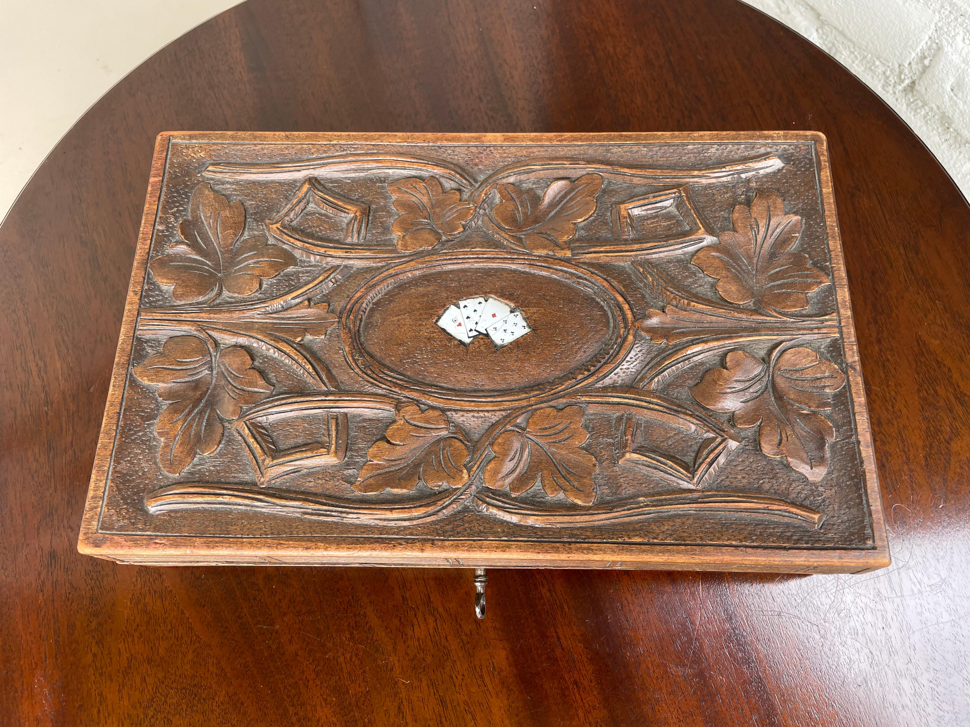 Entirely carved antique box for playing cards with inlaid, enameled miniature cards on top, ca 1880.

If you are a collector of rare and stylish hand carved Black Forest antiques in general and/or a collector of rare boxes for playing cards in