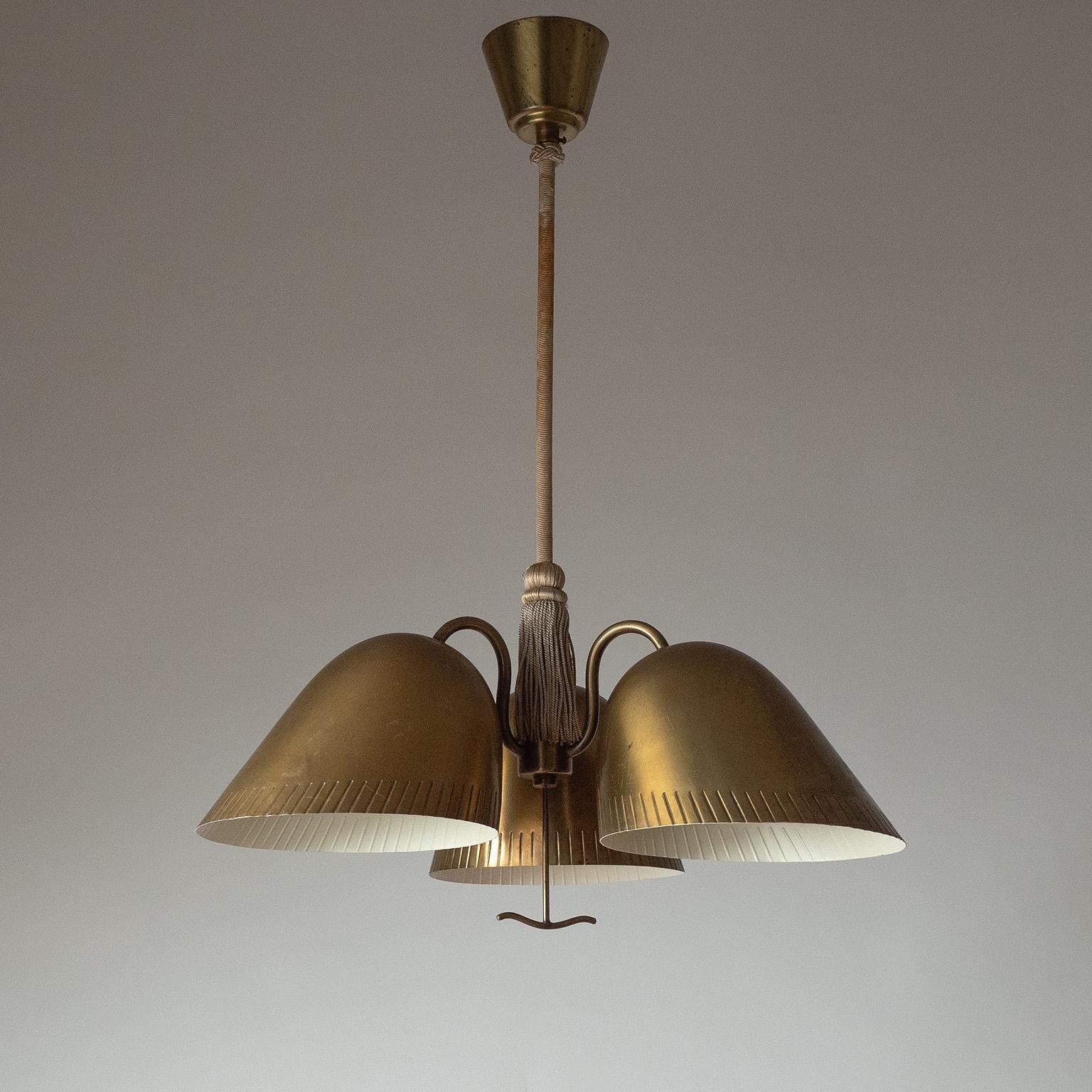 Very rare brass chandelier by Harald Notini for Böhlmarks from the 1940s. Three large frilled brass shades are suspended by a fabric covered stem with tassel decoration. Fair amount of patina on the brass and fabric with new professional paint on
