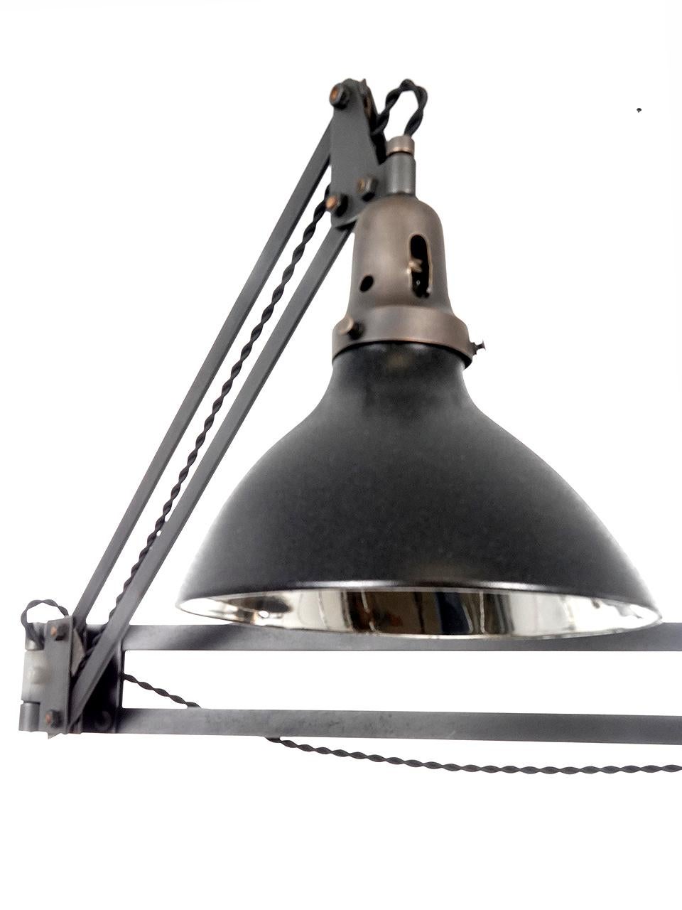 These Burton light company lamps are a rare find. They reach out 44 inches and feature a mercury glass shade. The shade is mirrored with a matte black pebbled finish outside. The patented Burton arms are well-articulated and easily move in all