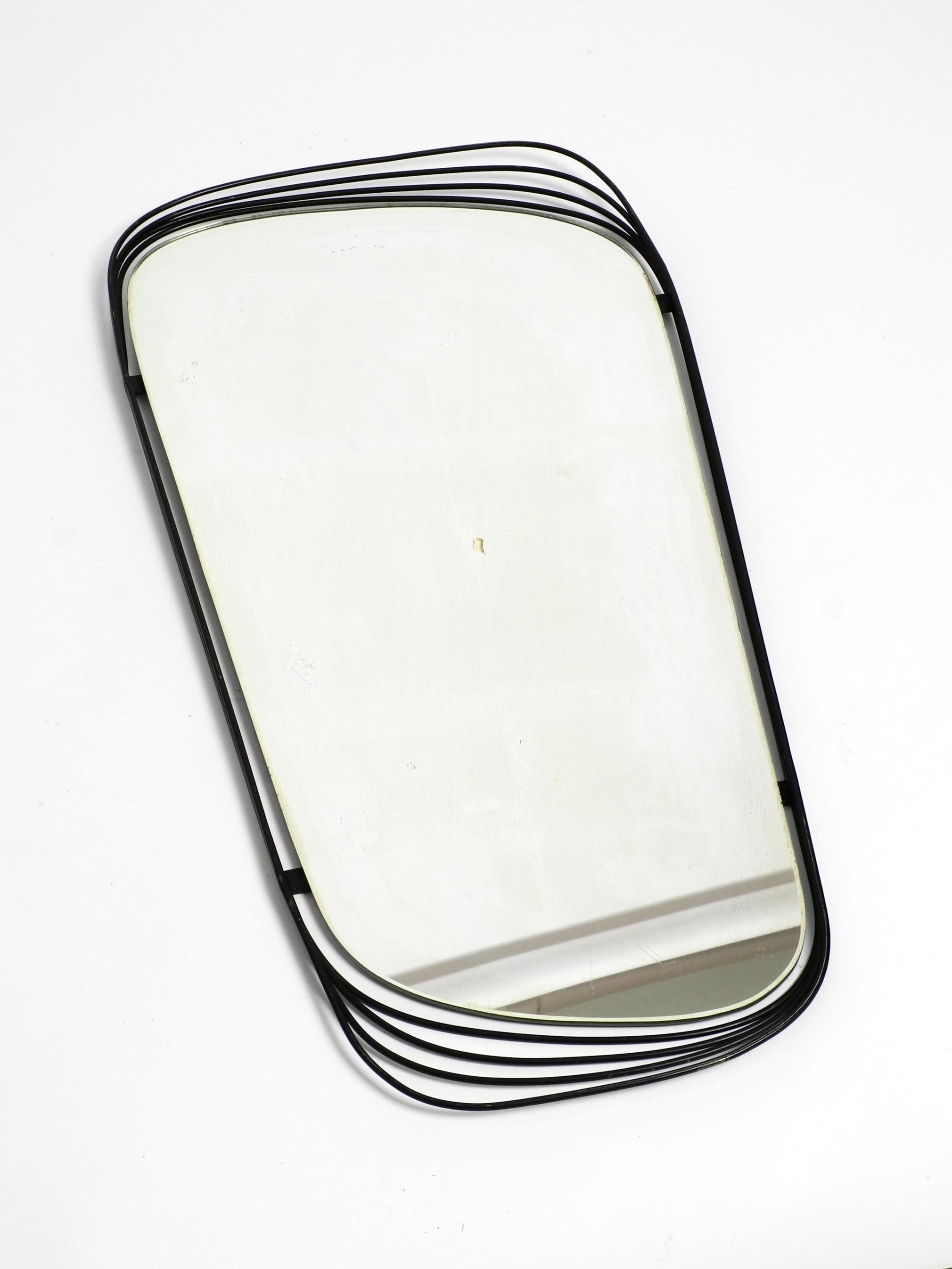 Very rare heavy Mid-Century Modern wall mirror with a black abstract metal frame.
Beautiful asymmetrical design. Made in Germany.
The mirror glass became slightly yellow and has become somewhat dull.
There is also one dark little spot in the