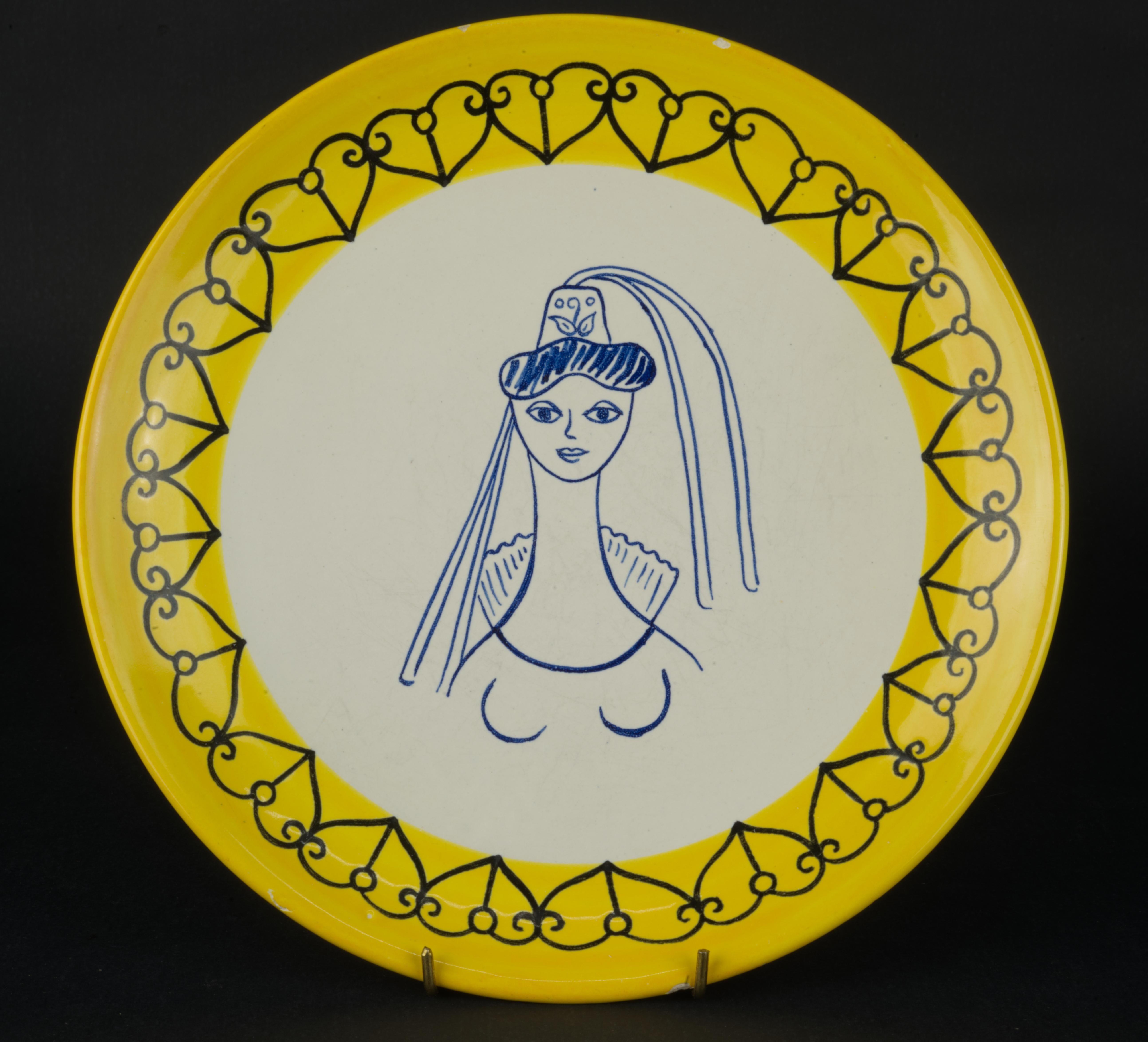  El raro plato de cerámica Henriot Quimper forma parte de la serie Sombrero diseñada por Claude Sanson, nieta de Jules Henriot, en la década de 1950. La serie está dedicada a los tocados tradicionales bretones de diversas zonas de Bretaña; esta