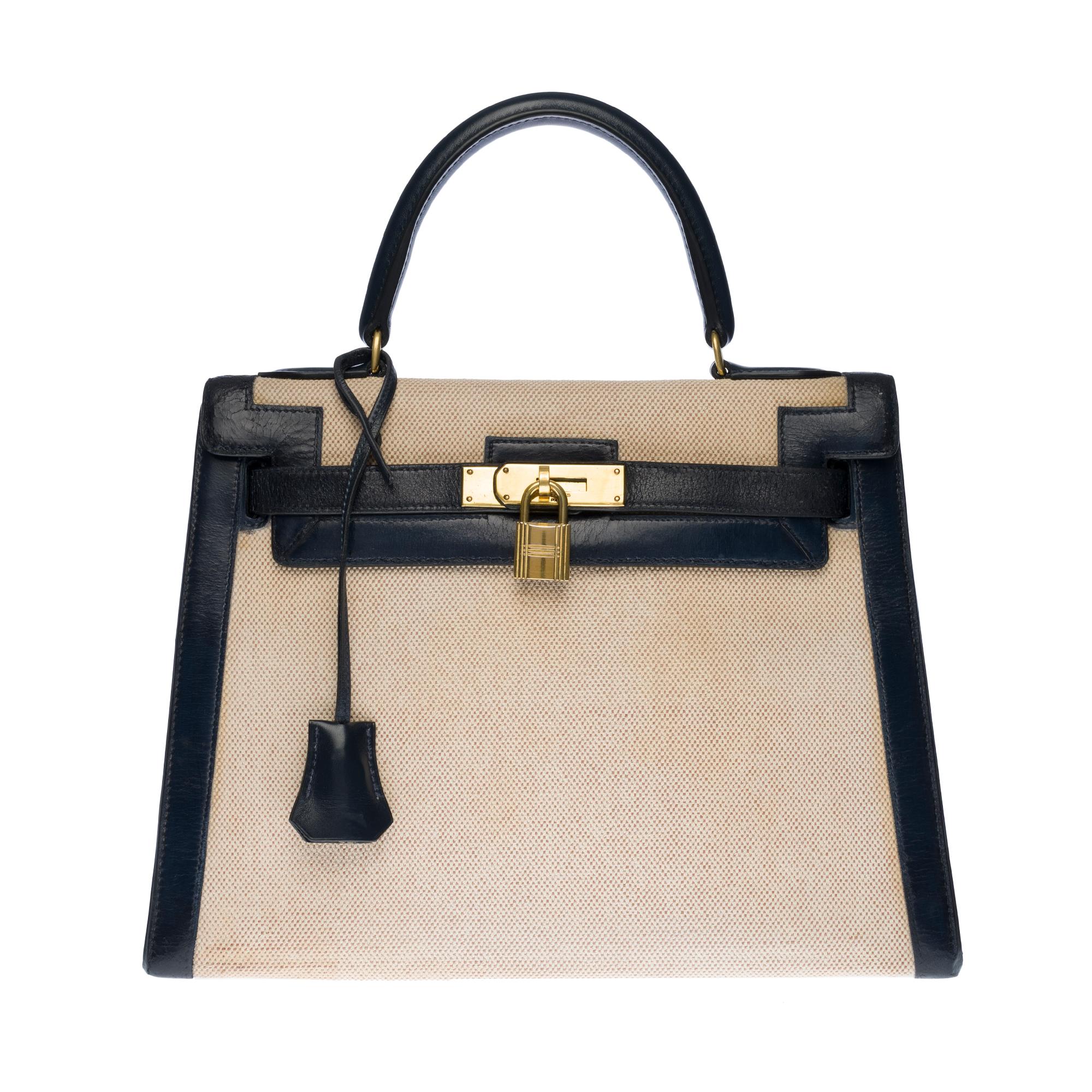 Rare Hermes Kelly 28 handbag in navy blue box leather and beige canvas, gold plated metal hardware, handle in navy blue leather allowing a hand support.

Closure by flap.
Lining in navy leather, a large patch pocket, a double patch