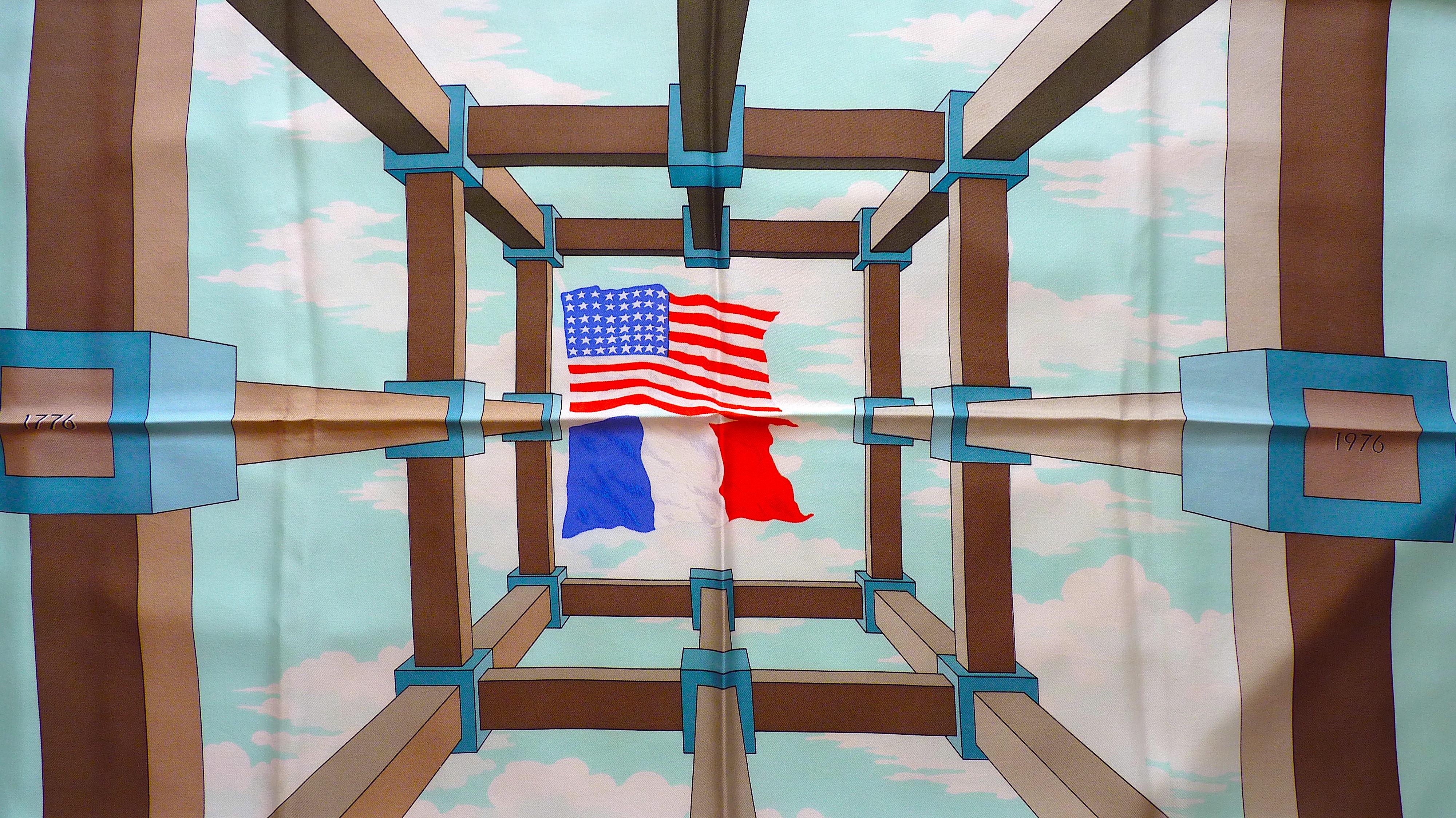 Très rare foulard Hermès Perspective Edition spéciale imprimée en 1976 pour le Bicentenaire des Etats-Unis d'Amérique, et pour célébrer l'amitié franco-américaine.
Les drapeaux américain et français sont au centre du motif, et la mention 17 mai