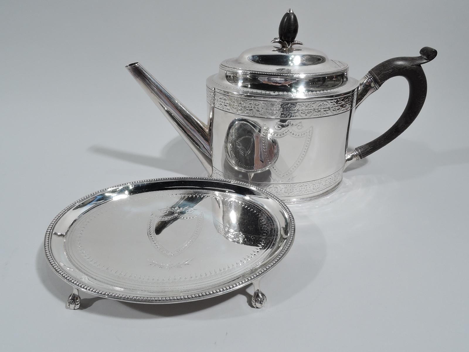 George III sterling silver teapot on stand. Made by Hester Bateman in London in 1789. Teapot: Ovoid body with straight and tapering diagonal spout and capped looping handle. Cover hinged and raised with leaf-mounted ovoid stained-wood finial. Stand:
