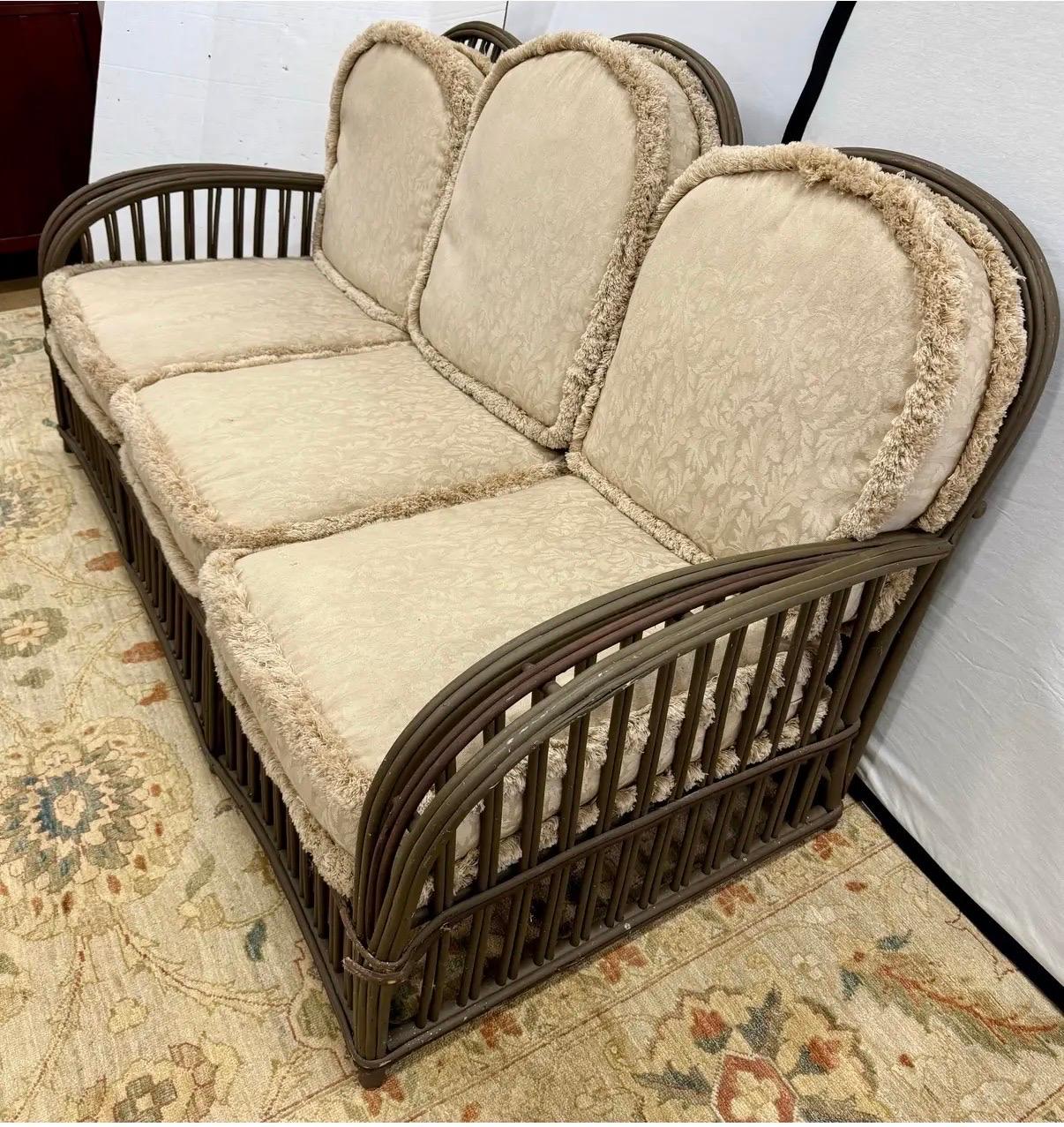 Expertly crafted in the 1940's, this generously scaled three-seat sofa showcases the classic stick rattan construction that made Heywood Wakefield a household name. The frame features gracefully arched arms and a rhythmic pattern of vertical rattan