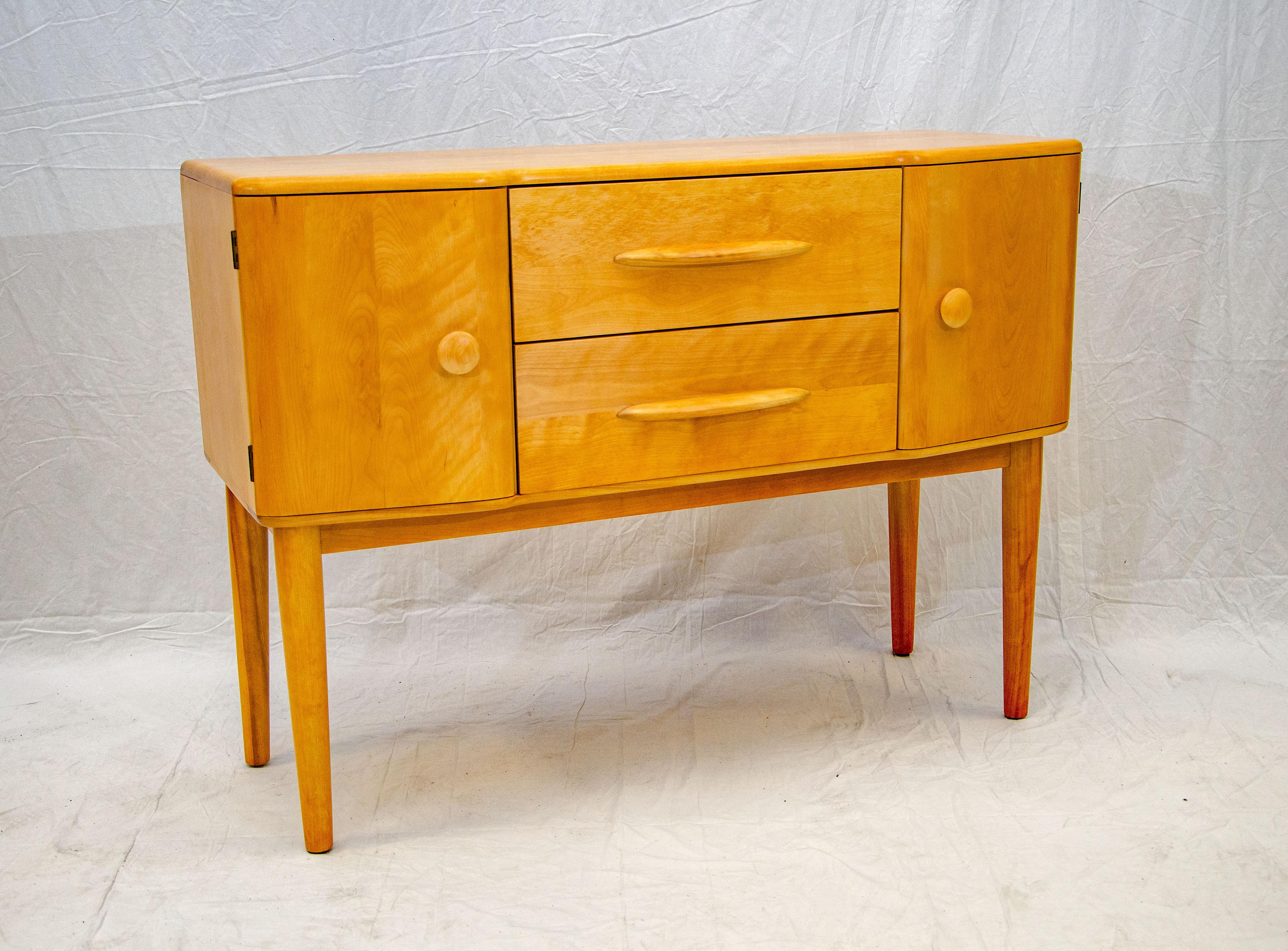 Hard to find Heywood Wakefield server on tall legs. The doors are at a slight angle and the two drawers are slightly recessed. The deep drawers provide ample storage space. This server was manufactured for only two years (1940-1942) and thus it is a