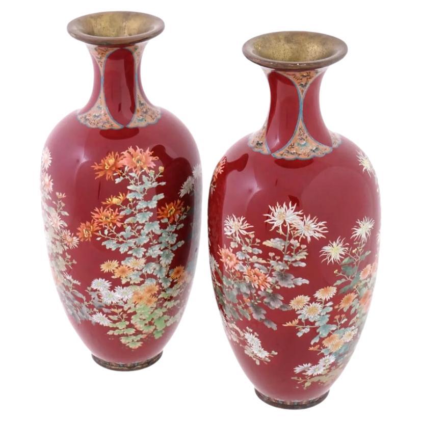 A pair of rare large high quality antique Japanese Meiji Era enamel over brass vases. The vases of amphora form with elegant narrow necks slightly expanding to the rim. The exterior is enameled with detailed polychrome images of blossoming flowers
