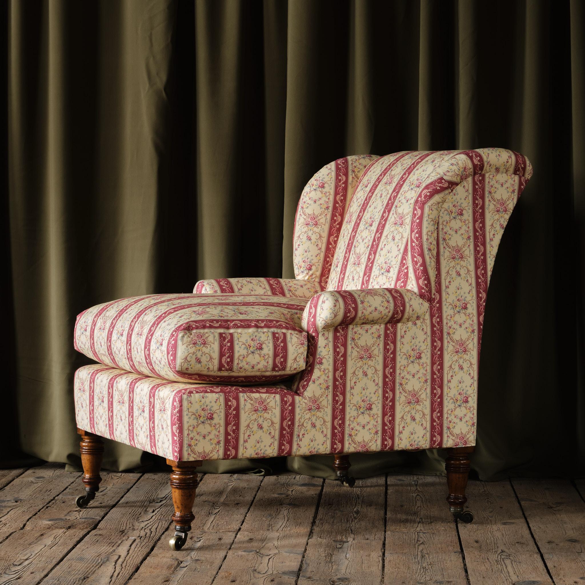 A wonderful and rare armchair by the renowned London makers Howard & Sons. Raised on 4 turned walnut legs and brass casters. The back left leg stamped with the serial number the makers name and address. The design of this model usually presents as a