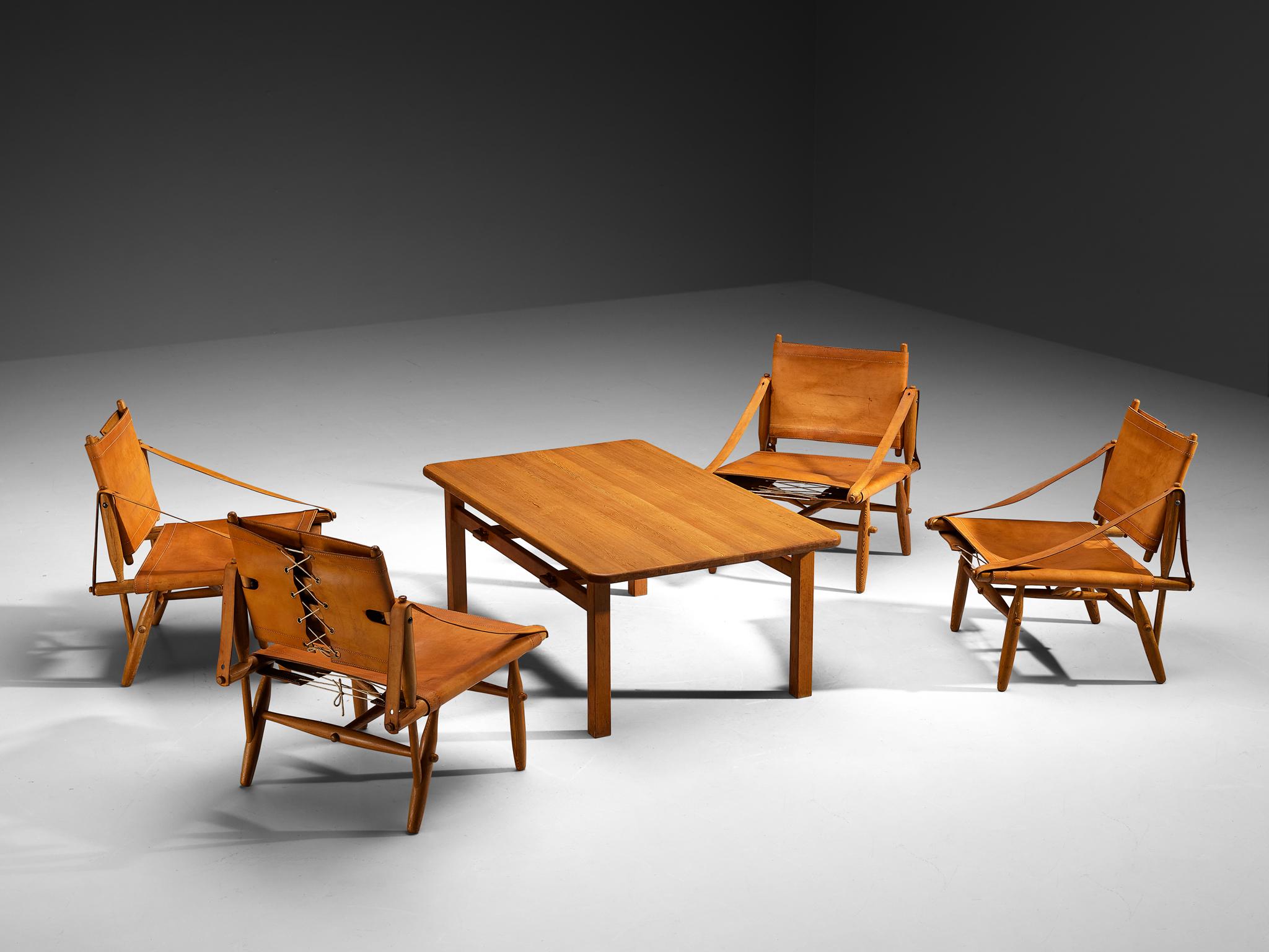 Ilmari Tapiovaara per Lukkiseppo, set di quattro poltrone 'Chaco' con tavolino, pelle, pino, ottone, corda, Finlandia, design 1958

Ti presentiamo uno squisito insieme di sedie lounge e un tavolino da caffè complementare, noto come collezione Chaco,