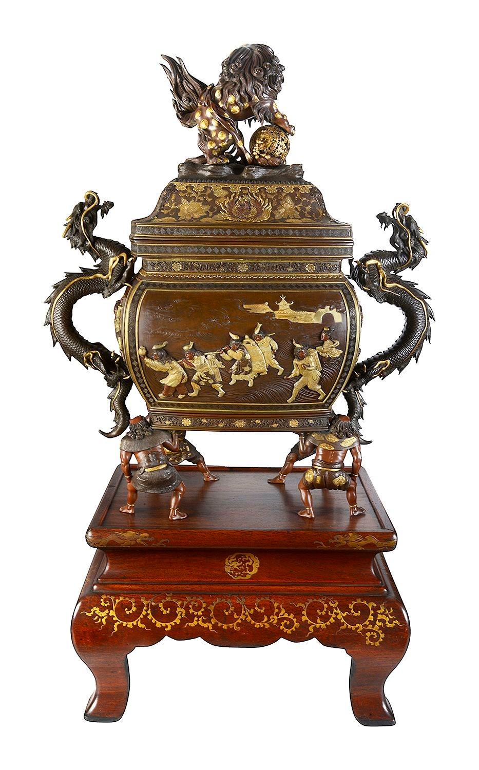 A magnificent Japanese Meiji period (1868-1912) patinated bronze overlay Koro on stand. The body of bellied rectangular section, the sides molded in low relief with various figural scenes, flanked by sinuous dragon-form handles, the domed cover
