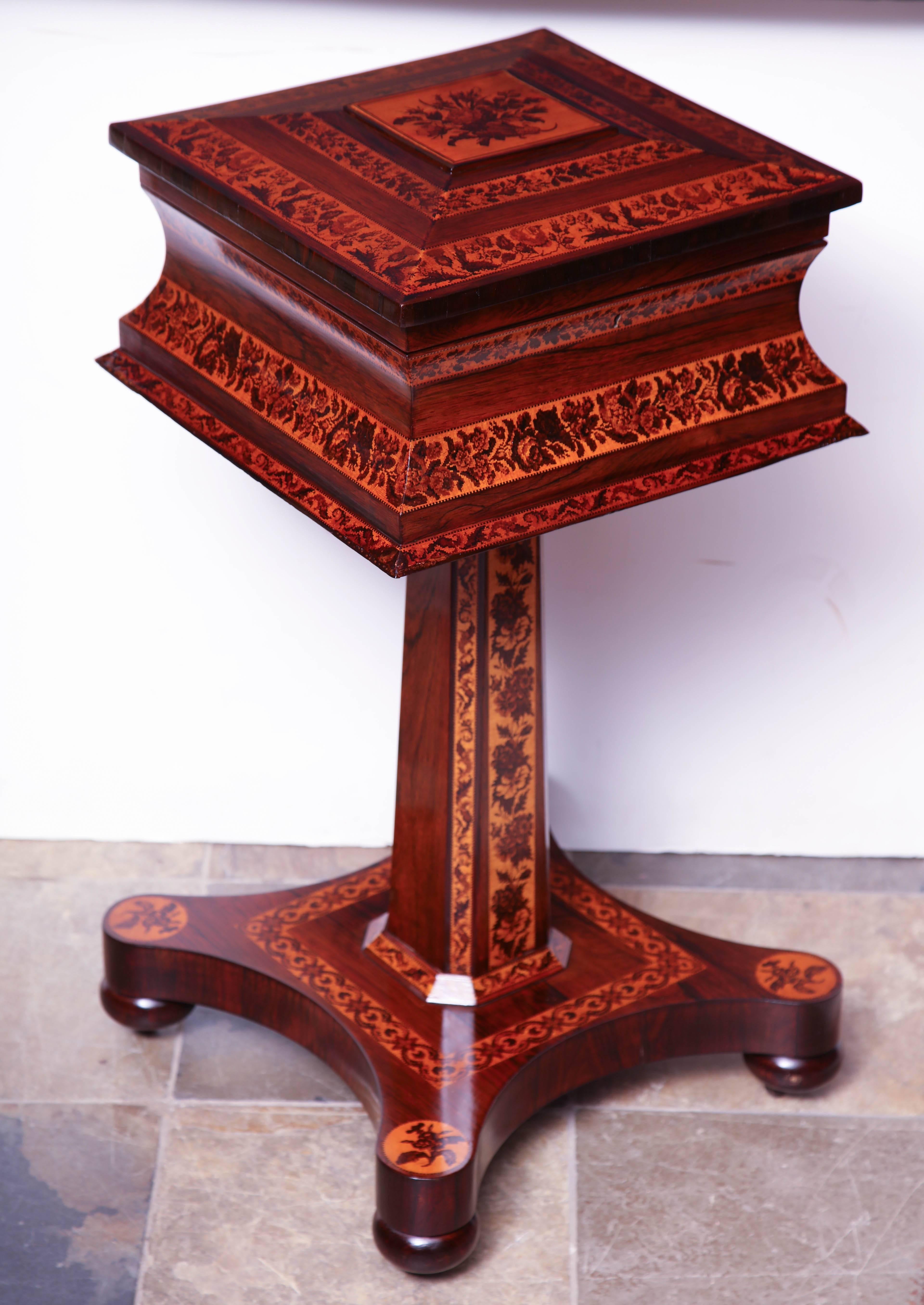 A fine and rare Irish mahogany elaborately inlaid lift top teapoy with a fitted interior having two lead glasses for mixing and raised on a pedestal base.
