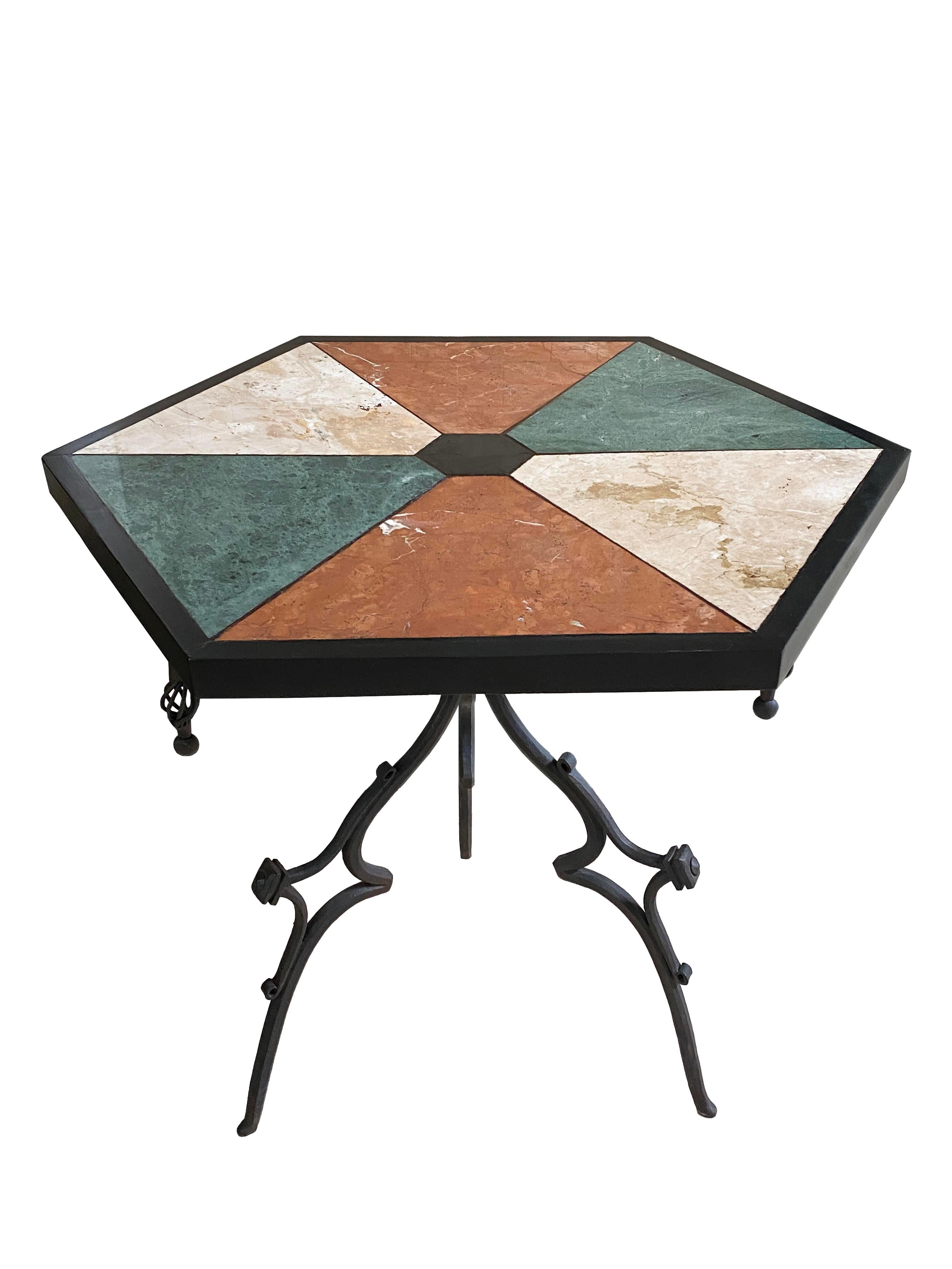 This distinctive accent end table features a hexagonal top inlaid with a vibrant arrangement of multi-colored marble and granite specimens. Each stone varies in hue and veining, creating a dynamic mosaic of natural patterns and textures. The