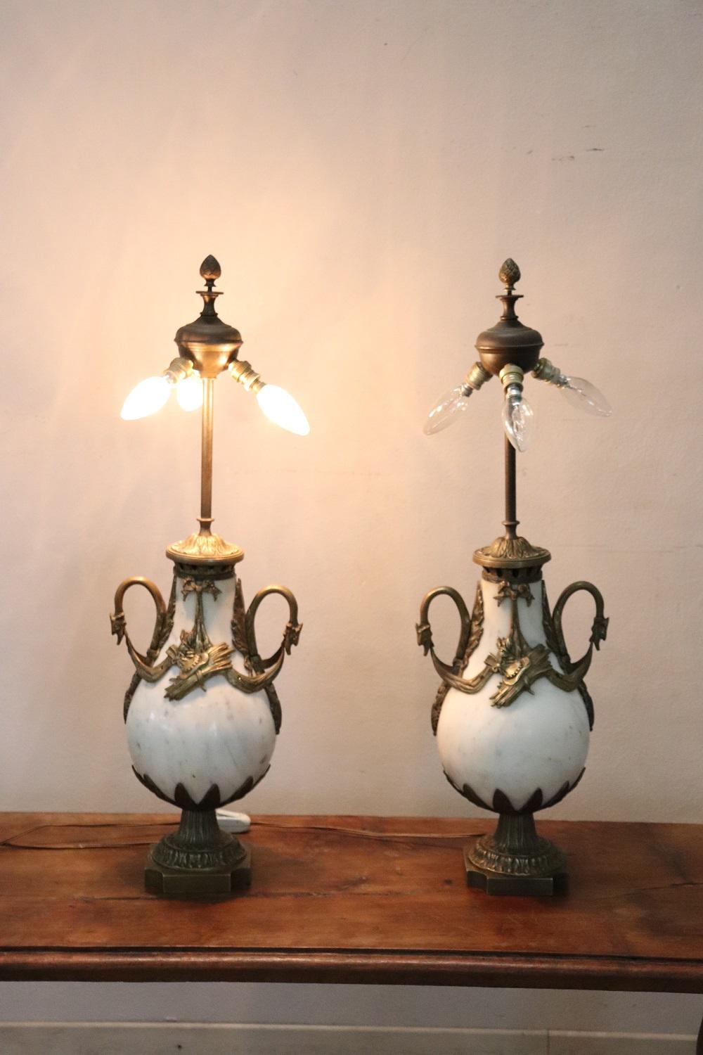 Beautiful and rare Italian pair of table lamps of the period art nouveau. The body of the lamps is in precious white Carrara marble in the shape of a drop. The marble is embellished with finely chiseled gilt bronze decorations. The gilded bronze has