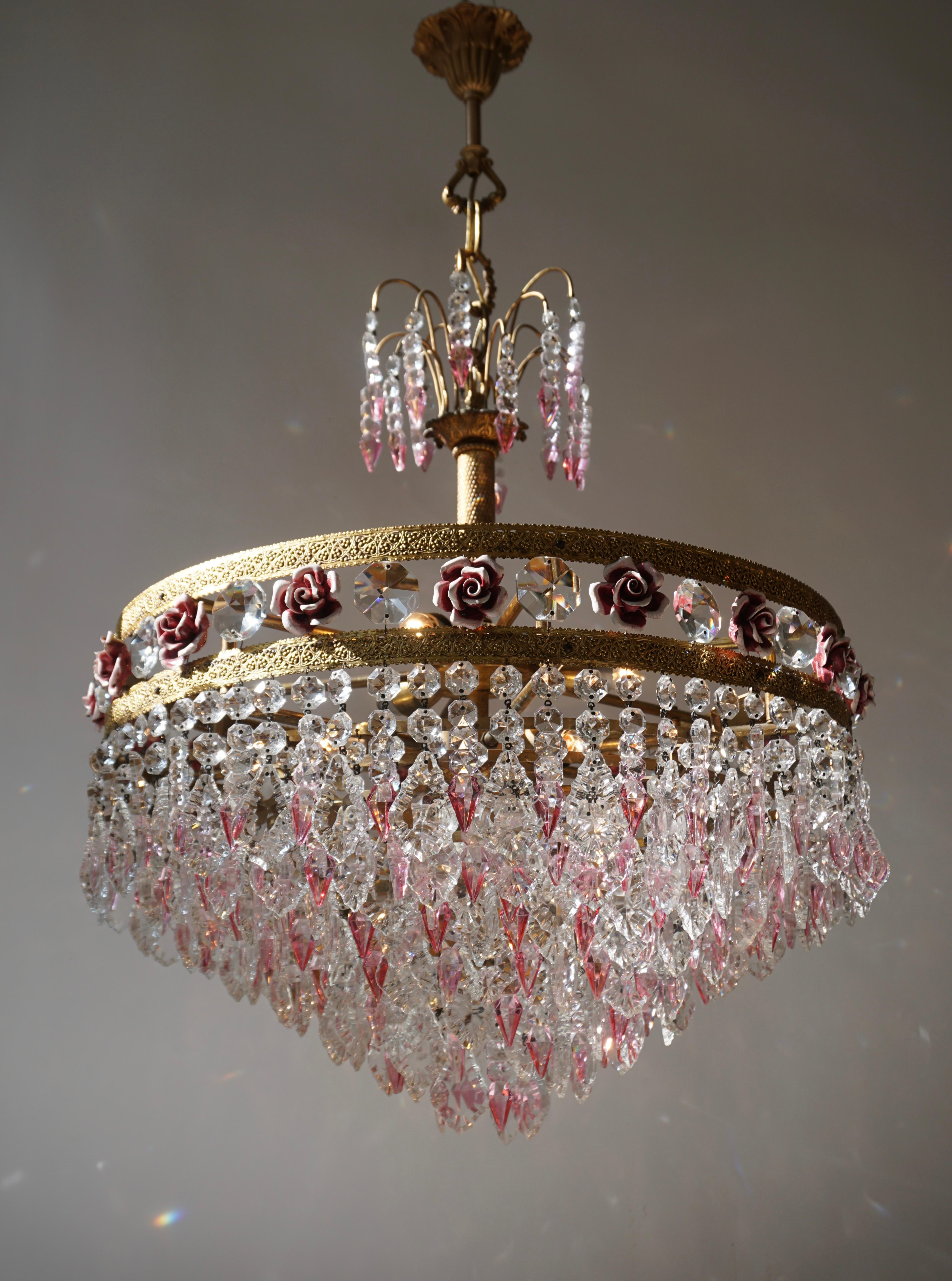Elegante Italian brass chandelier with pink crystals and pink porcelain flowers.

The light requires seven single E14 screw fit lightbulbs (40Watt max.) LED compatible.

Measures: Diameter 61 cm.
Height fixture 75 cm.
Total height 95 cm.