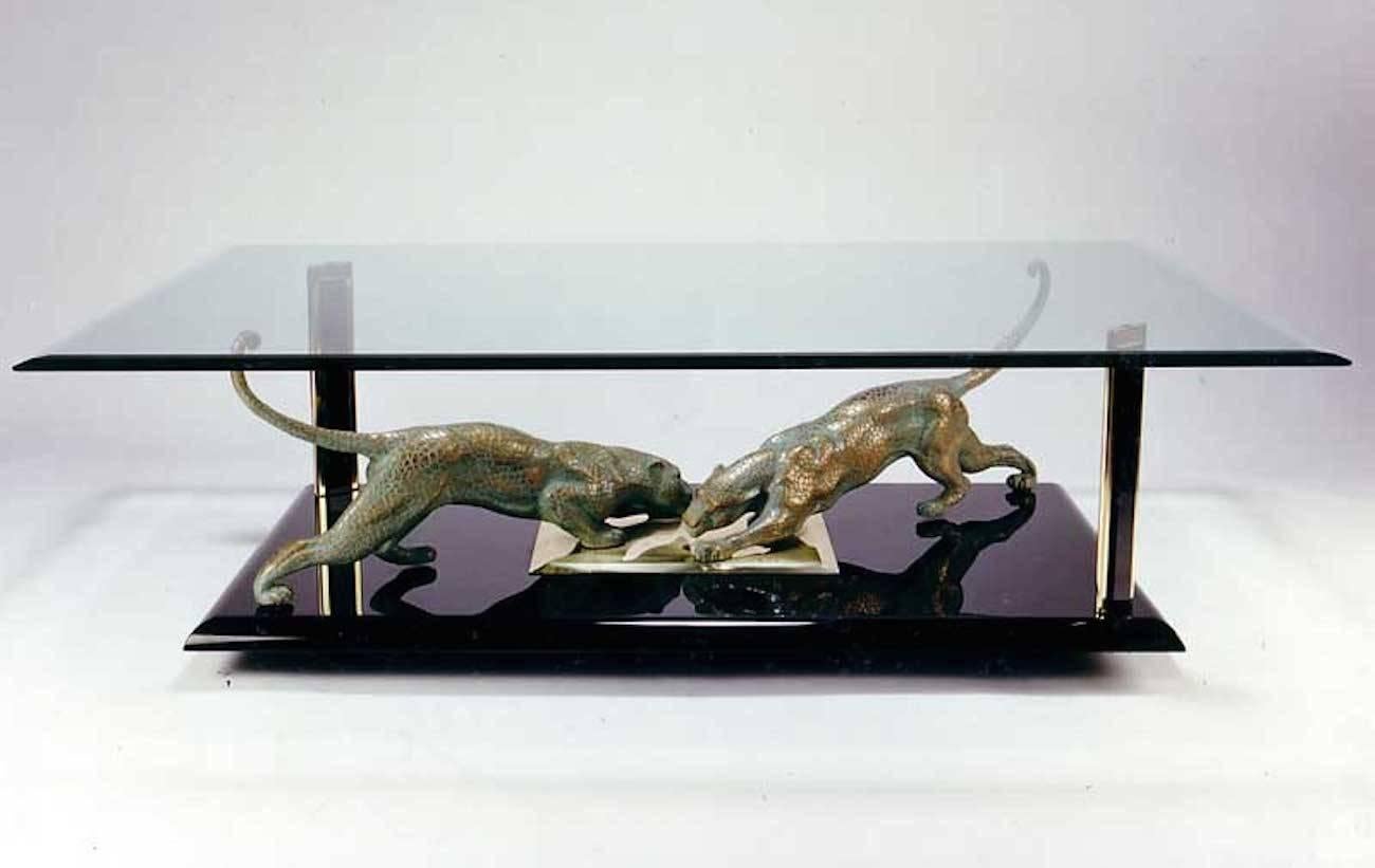 Unusual and rare 1970s Italian coffee table with gilt bronze sculpture of panthers on a black lacquered base and a clear rectangular glass top.

 