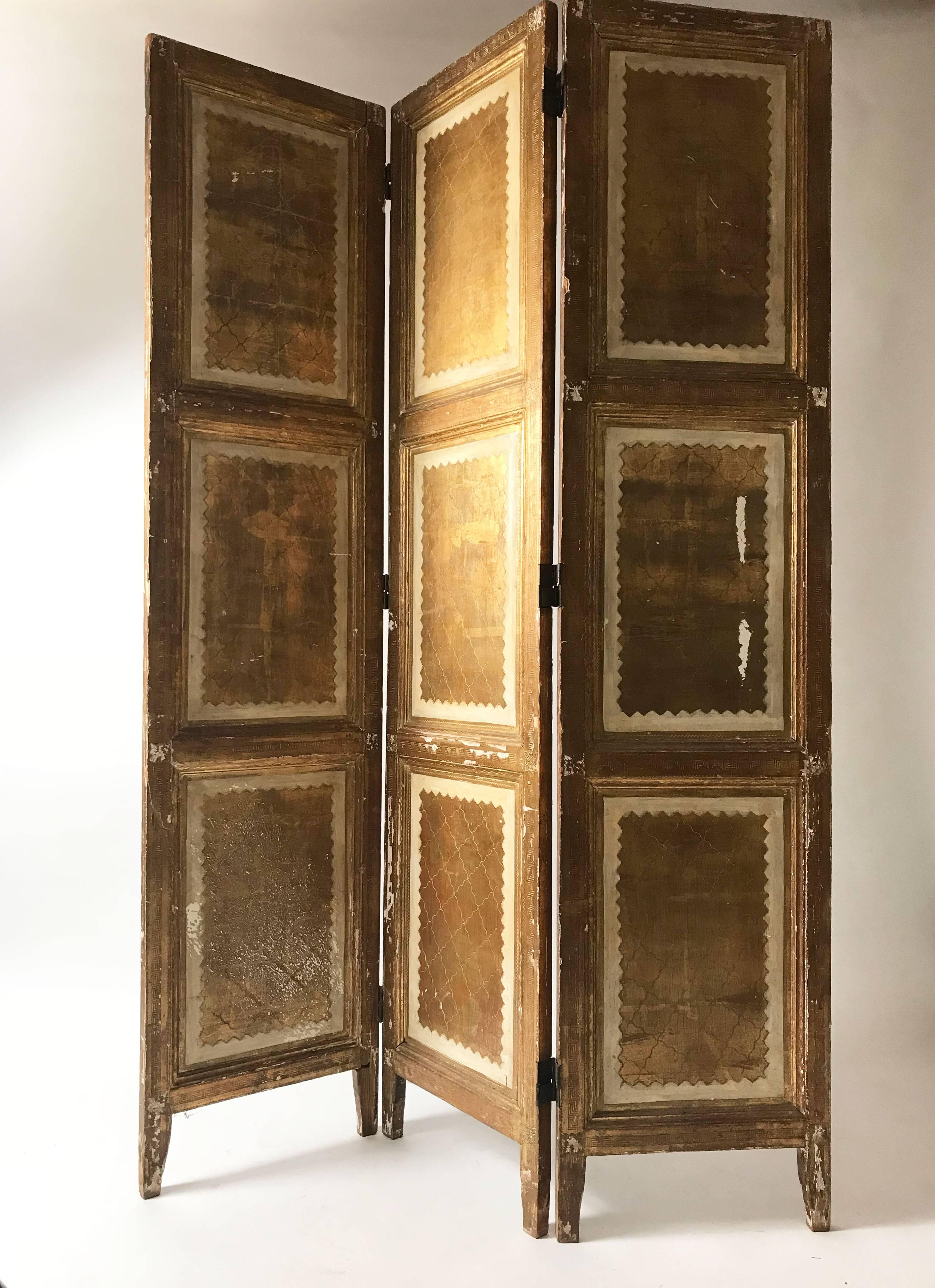 A very special Italian Florentine room divider or dressing screen. Gilded laurel motifs on a cream background. Significant wear to one of the panels but in general the patina only adds to the vintage feel. Three panels. Made in Italy.