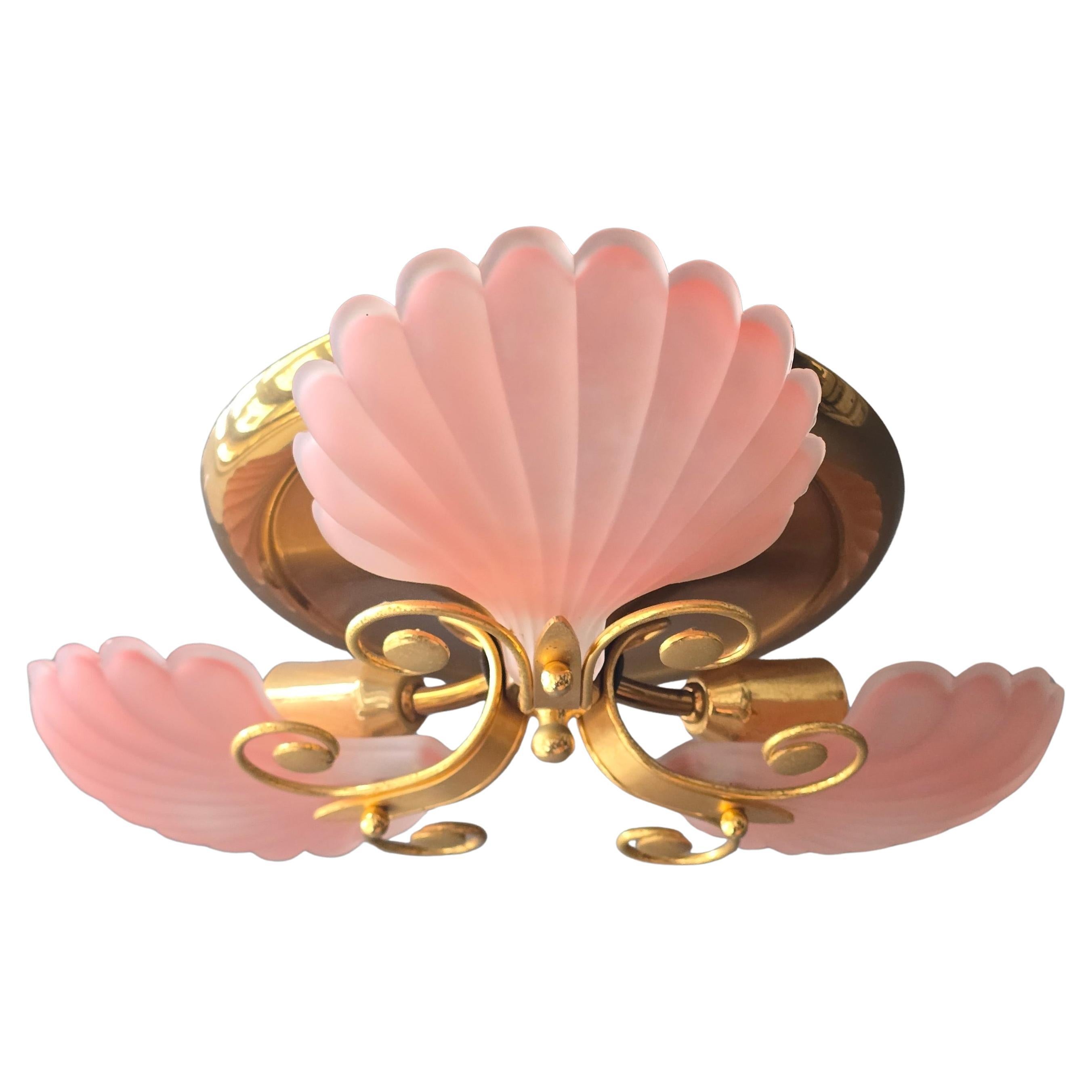 Elegante lámpara de techo de mediados de siglo con tres pantallas de cristal satinado en forma de concha en un refinado tono rosa pastel, combinadas con una cálida estructura de metal dorado. La suave difusión del cristal crea un resplandor