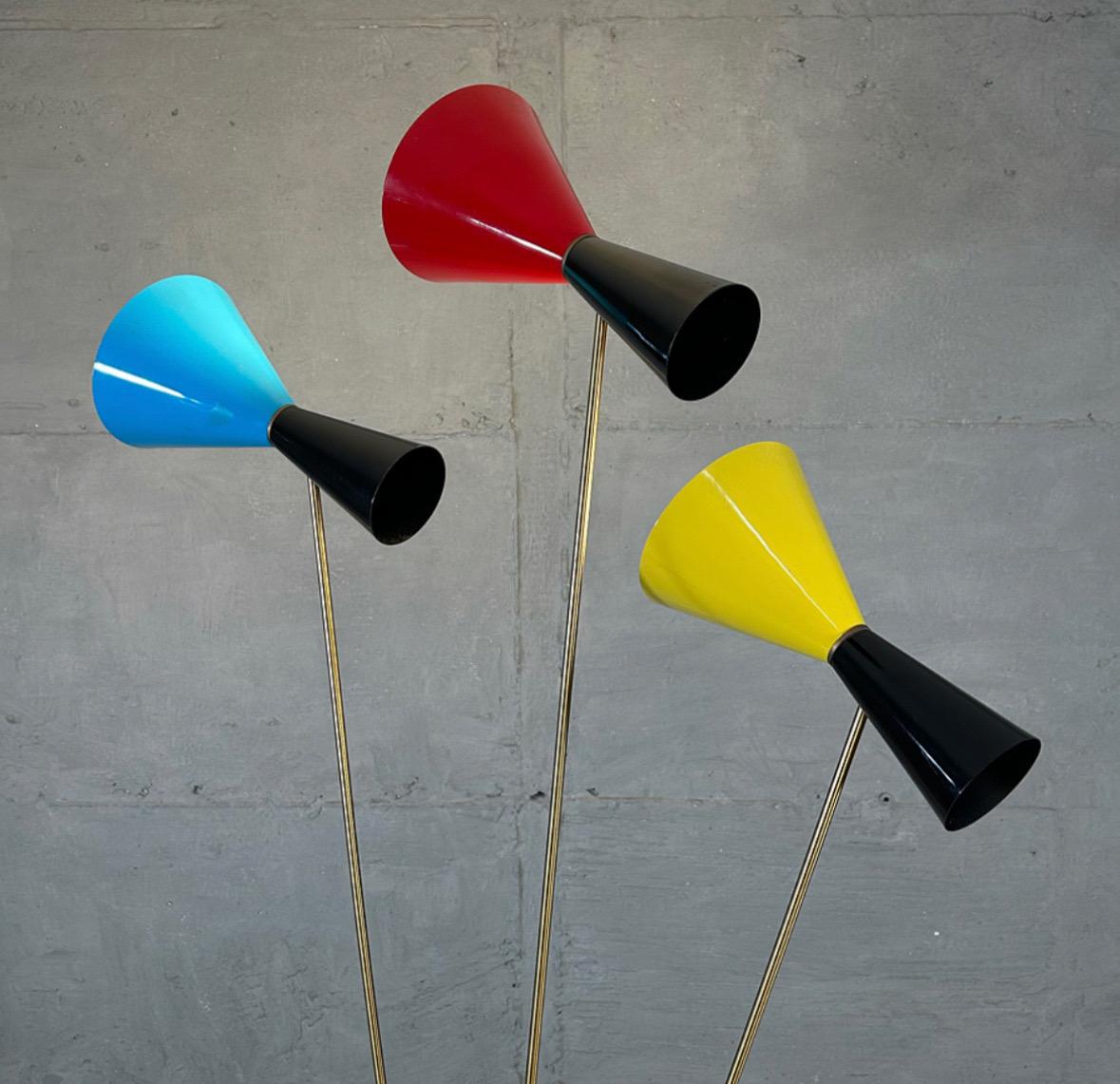 A remarkably rare and gorgeous Italian Stilnovo Three-Arm Tripod Floor Lamp from the 1960’s. 
Long solid brass tripod legs link to the central huge puck-like structure made of brass, from which three brass pedestals support the very long brass arms.
